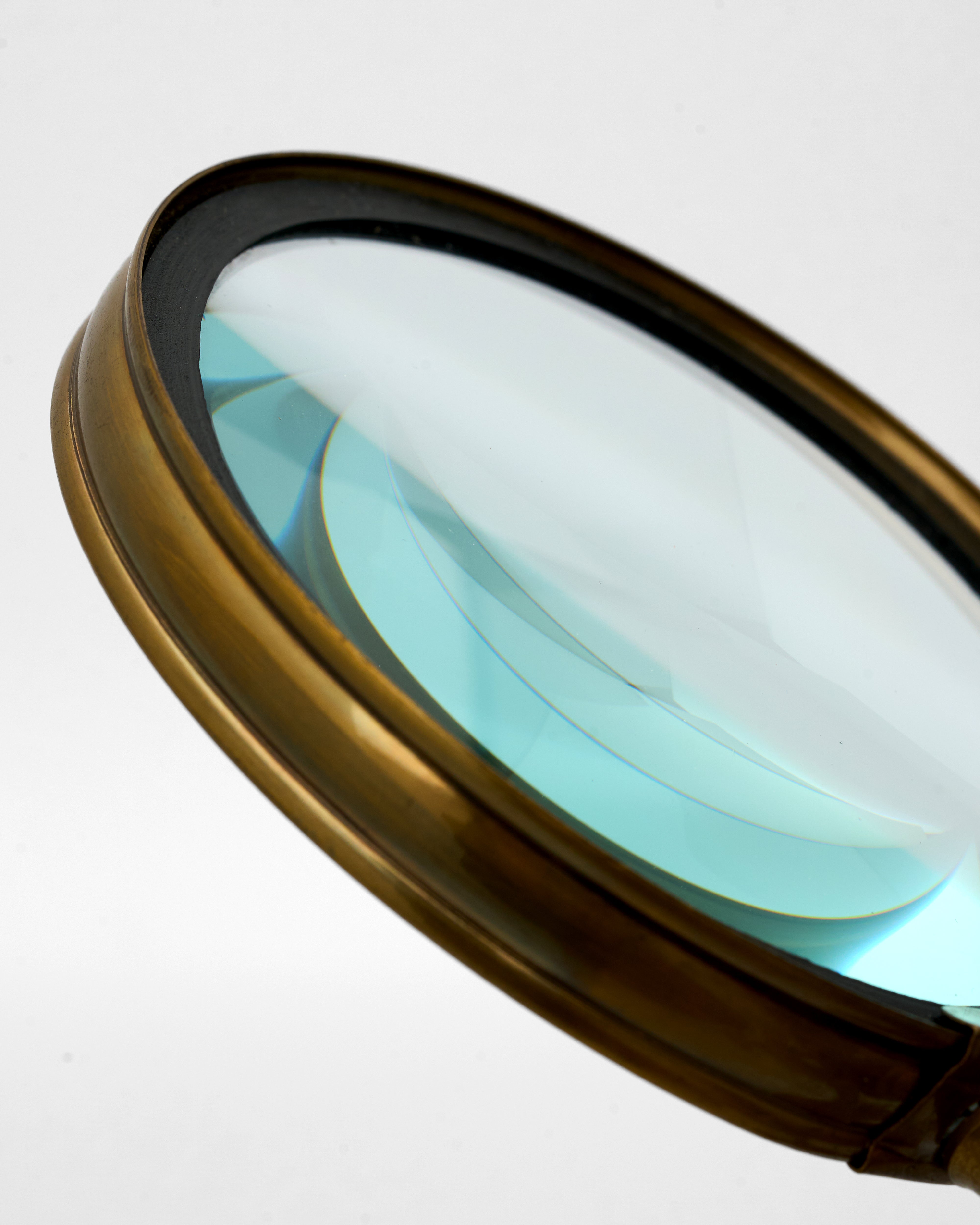 Round magnifying glass with a bronze frame on a white background