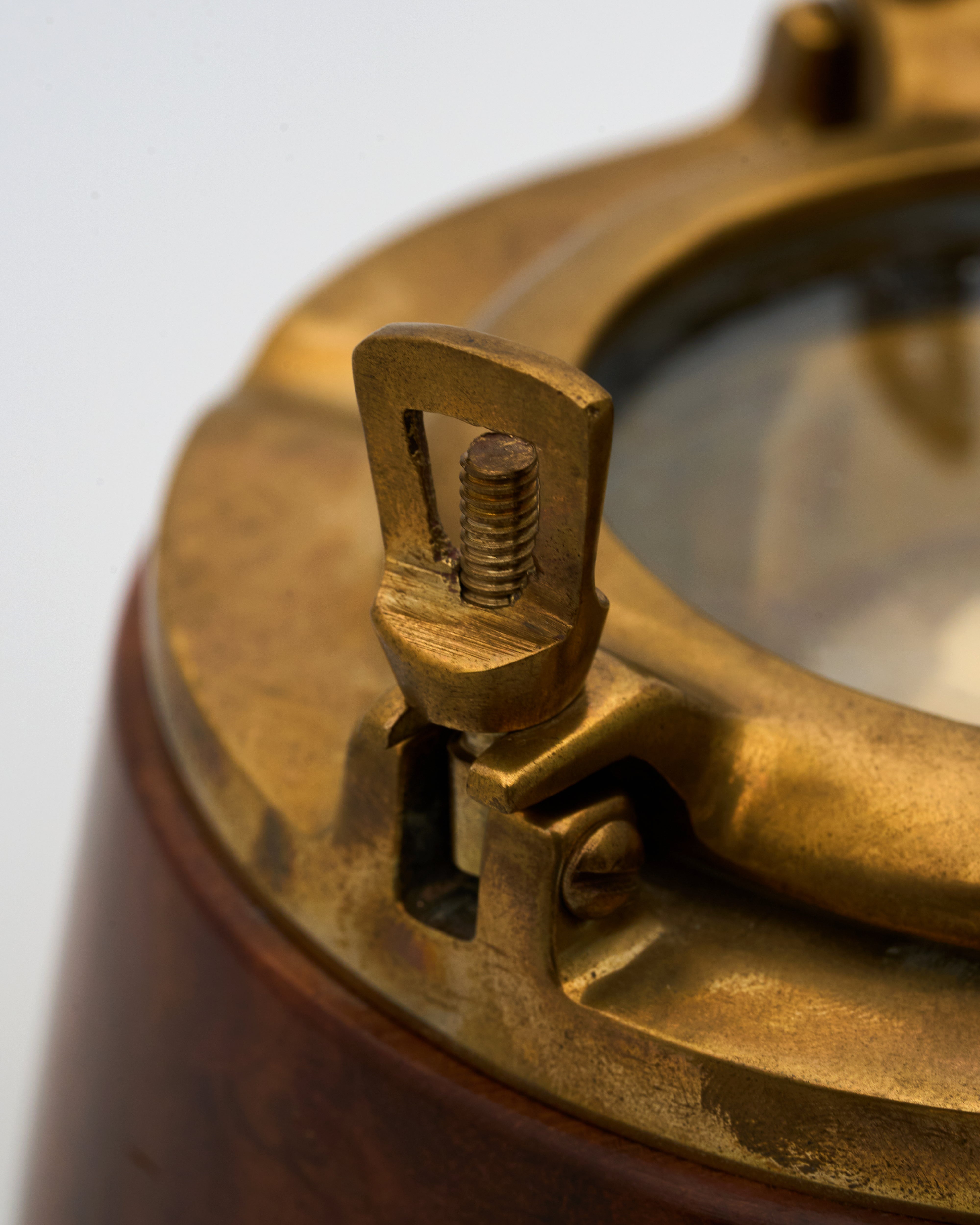 Close-up of a brass vintage ashtray with a wooden base on a light gray background