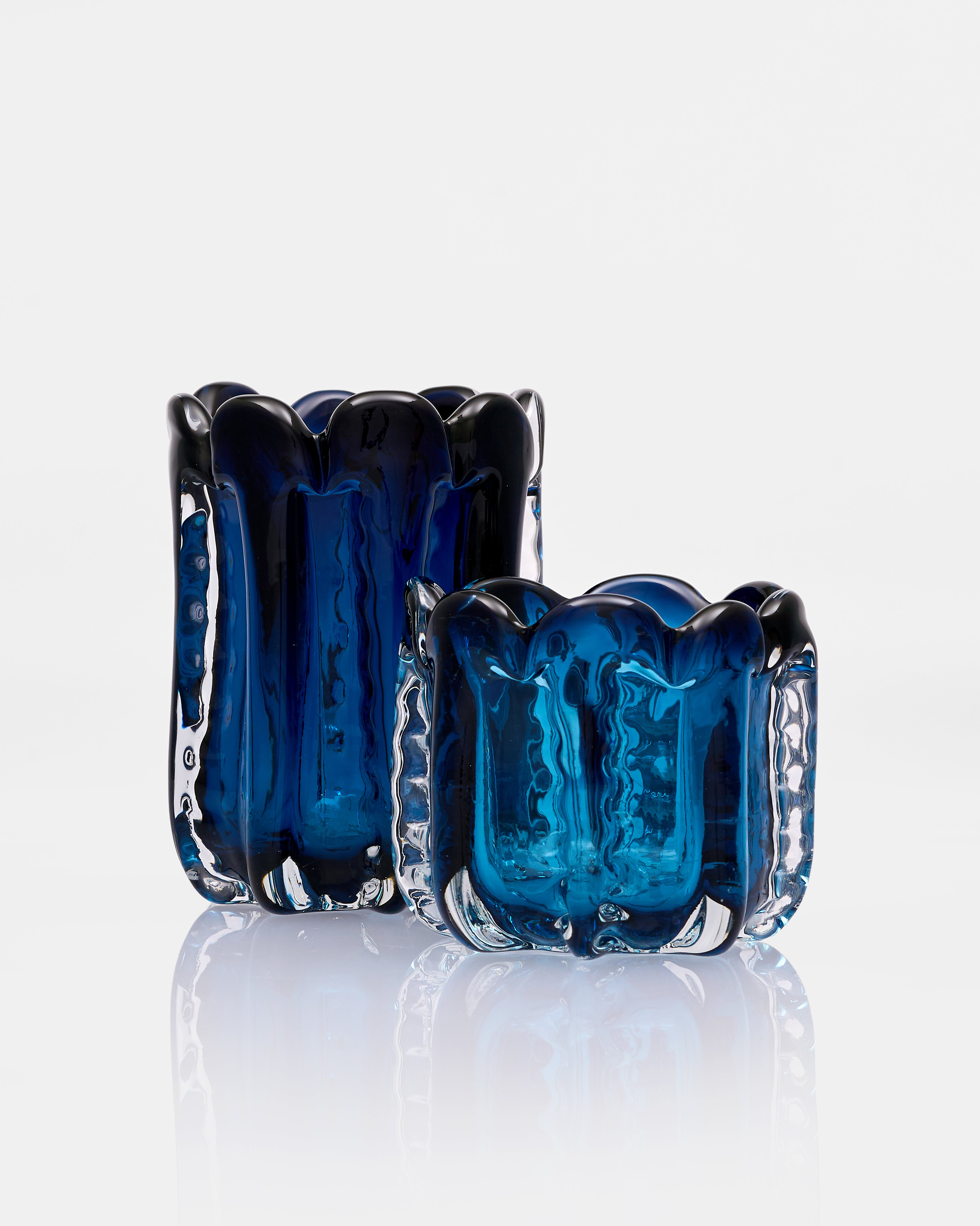 Two blue glass candle holders on a white background