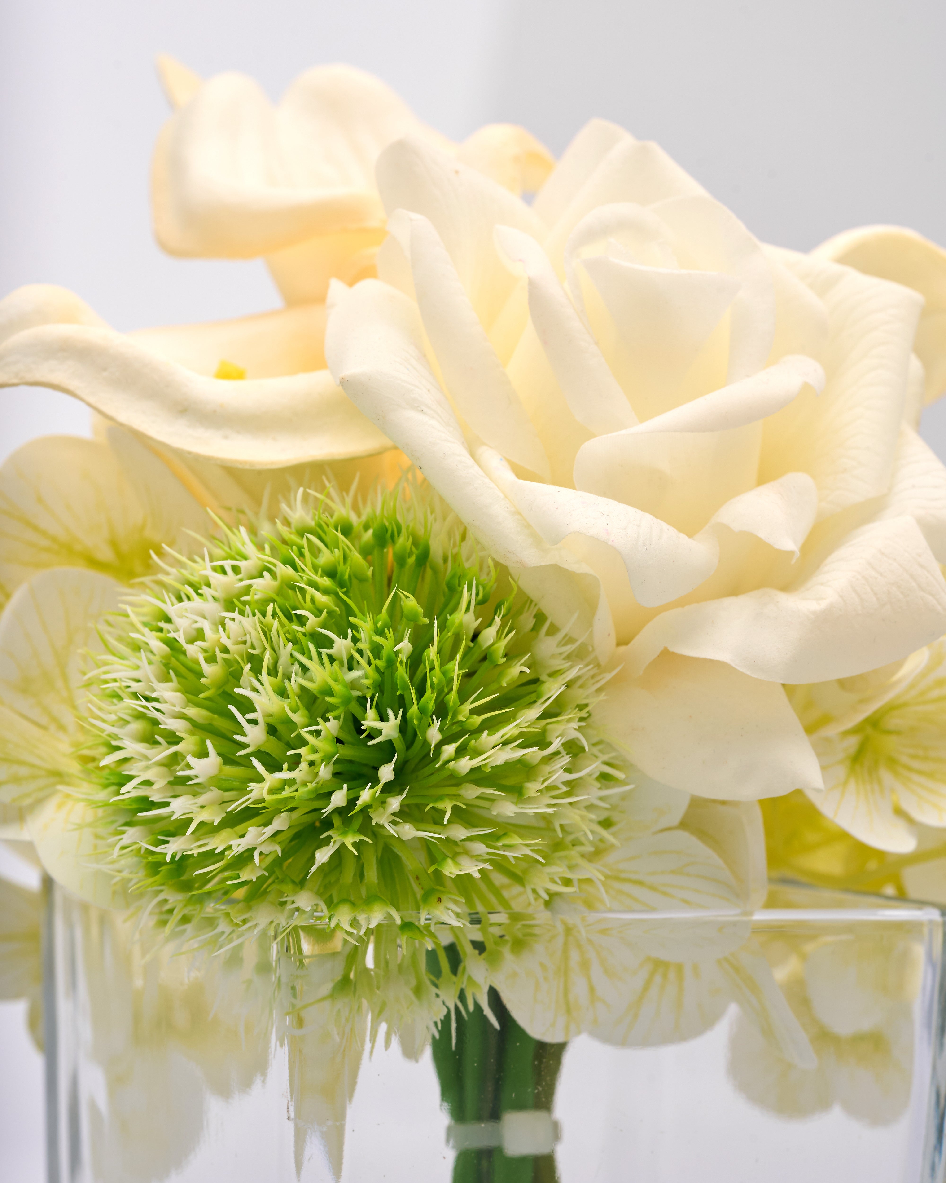 Bouquet of white flowers with a green center in a clear vase on a light gray background