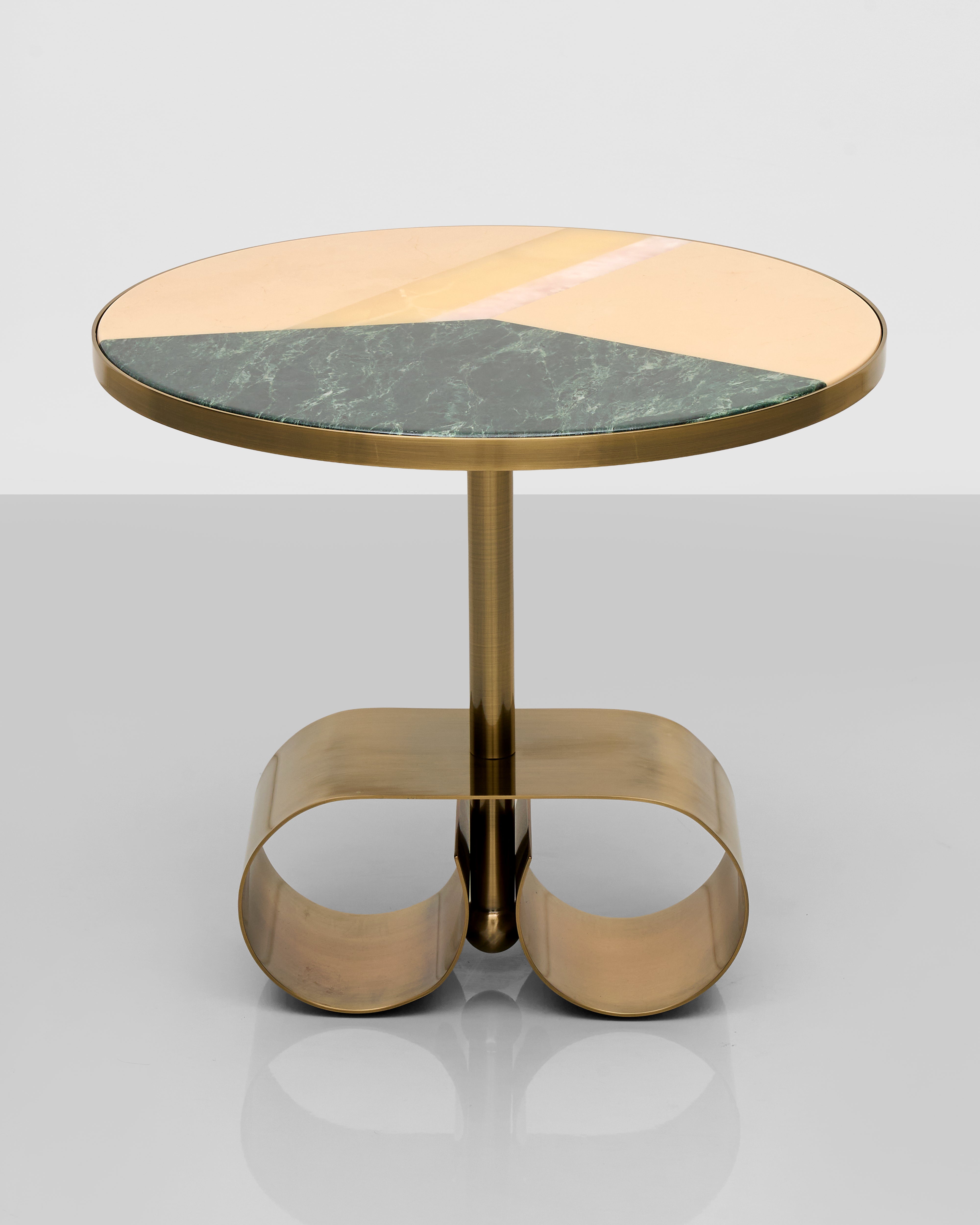 Small round table with brass base and marble top on a light gray background
