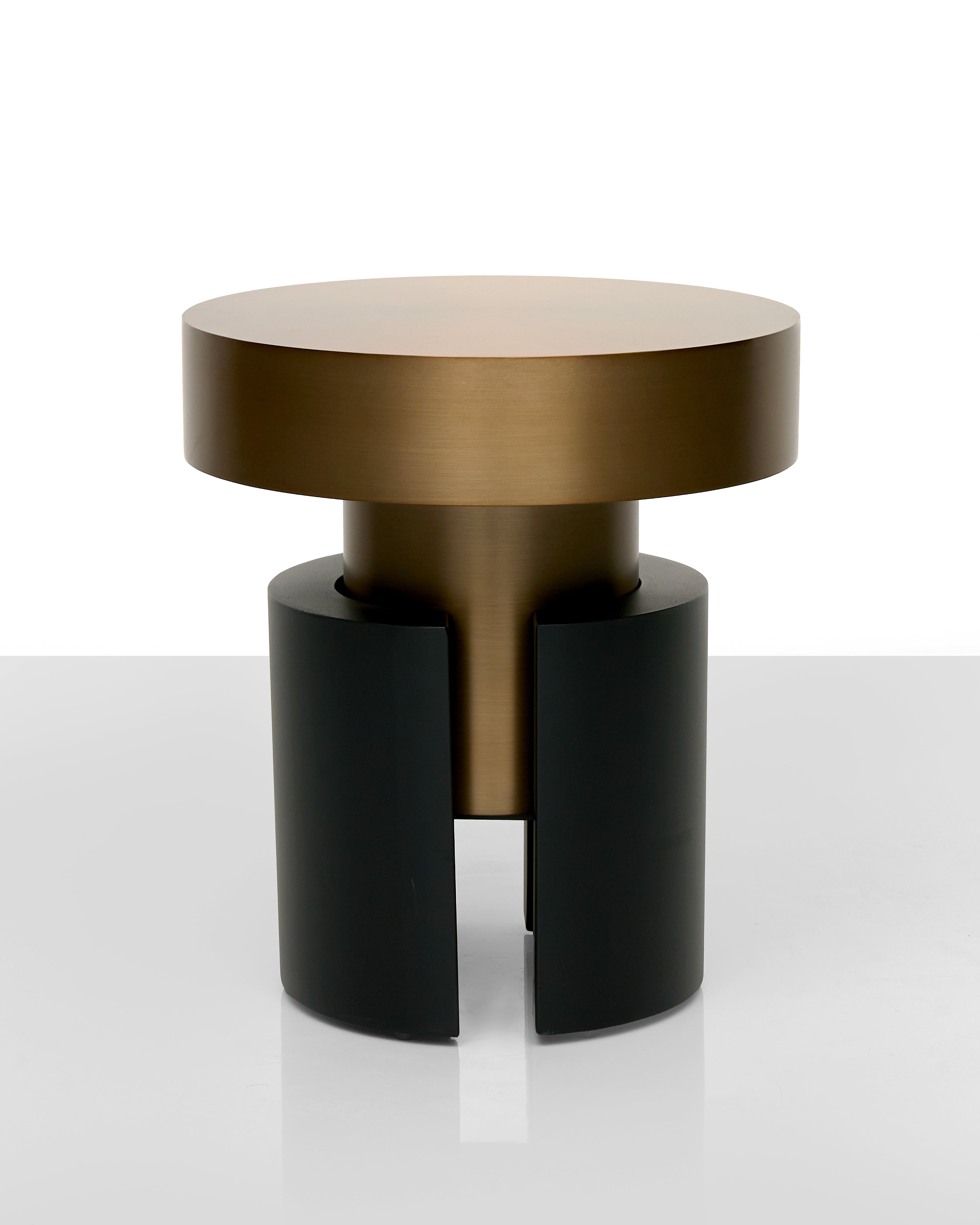 Modern side table with bronze top and black cylindrical base on a white background