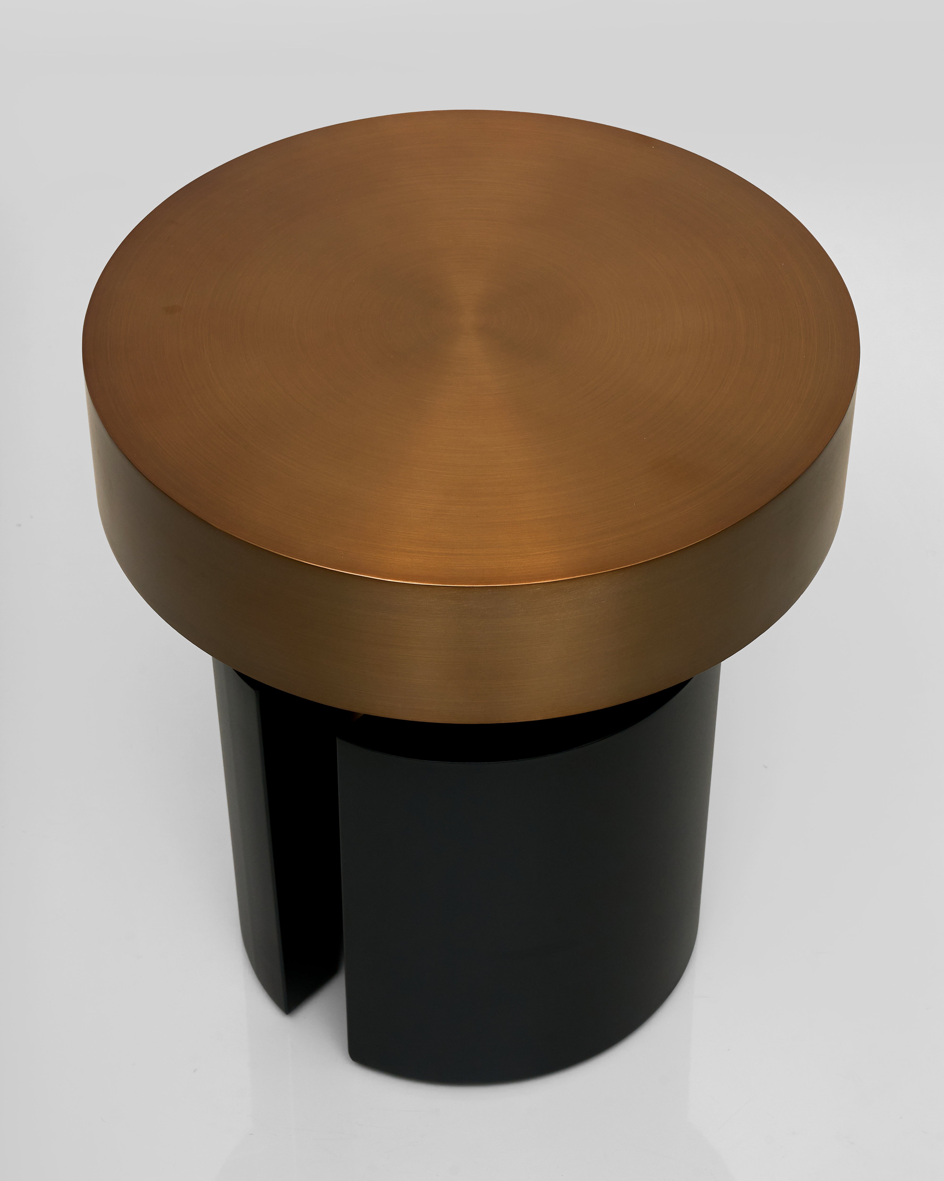 Round metallic stool with bronze top and black cylindrical base on a white background