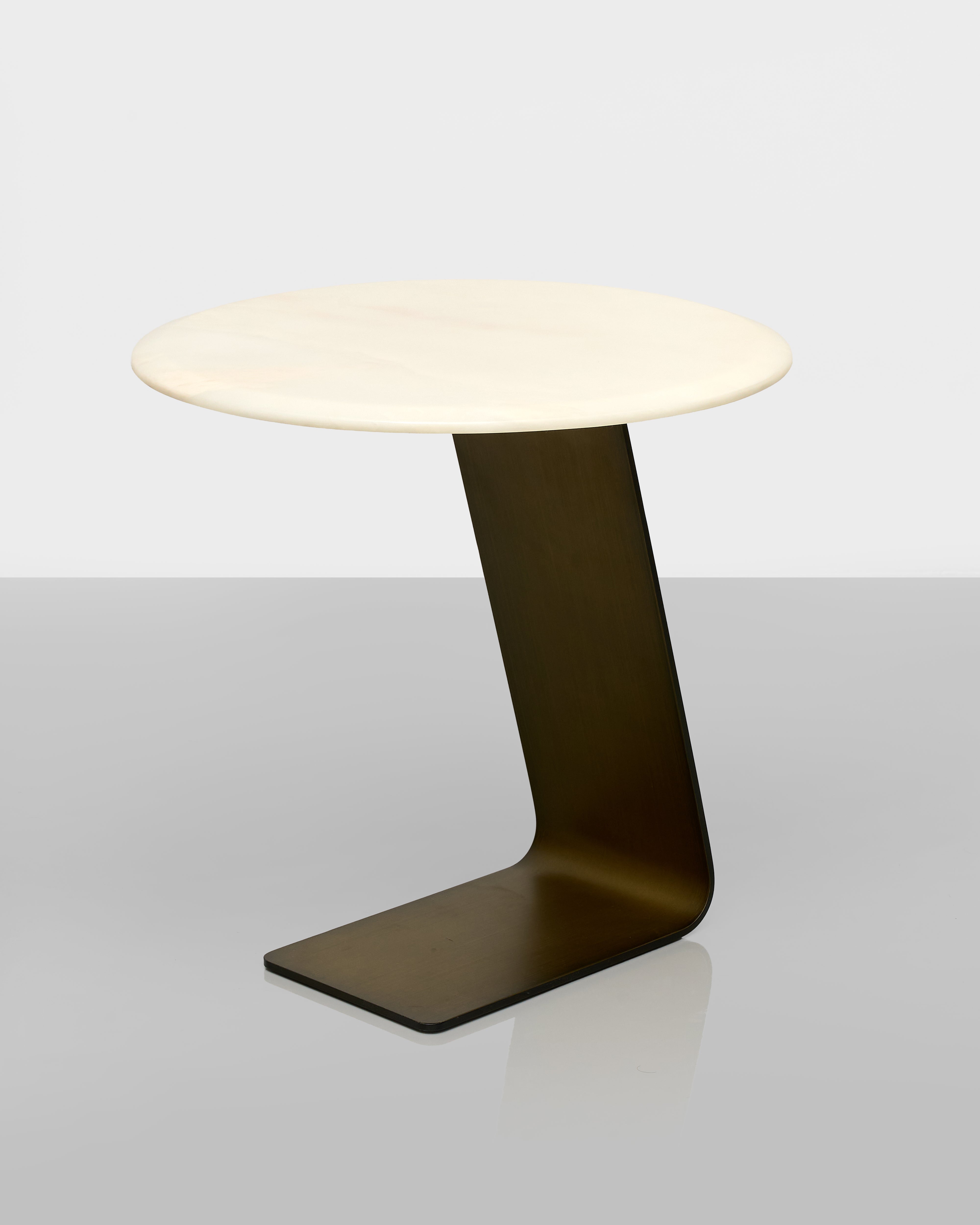 Modern side table with a white round top and black curved base on a light gray background
