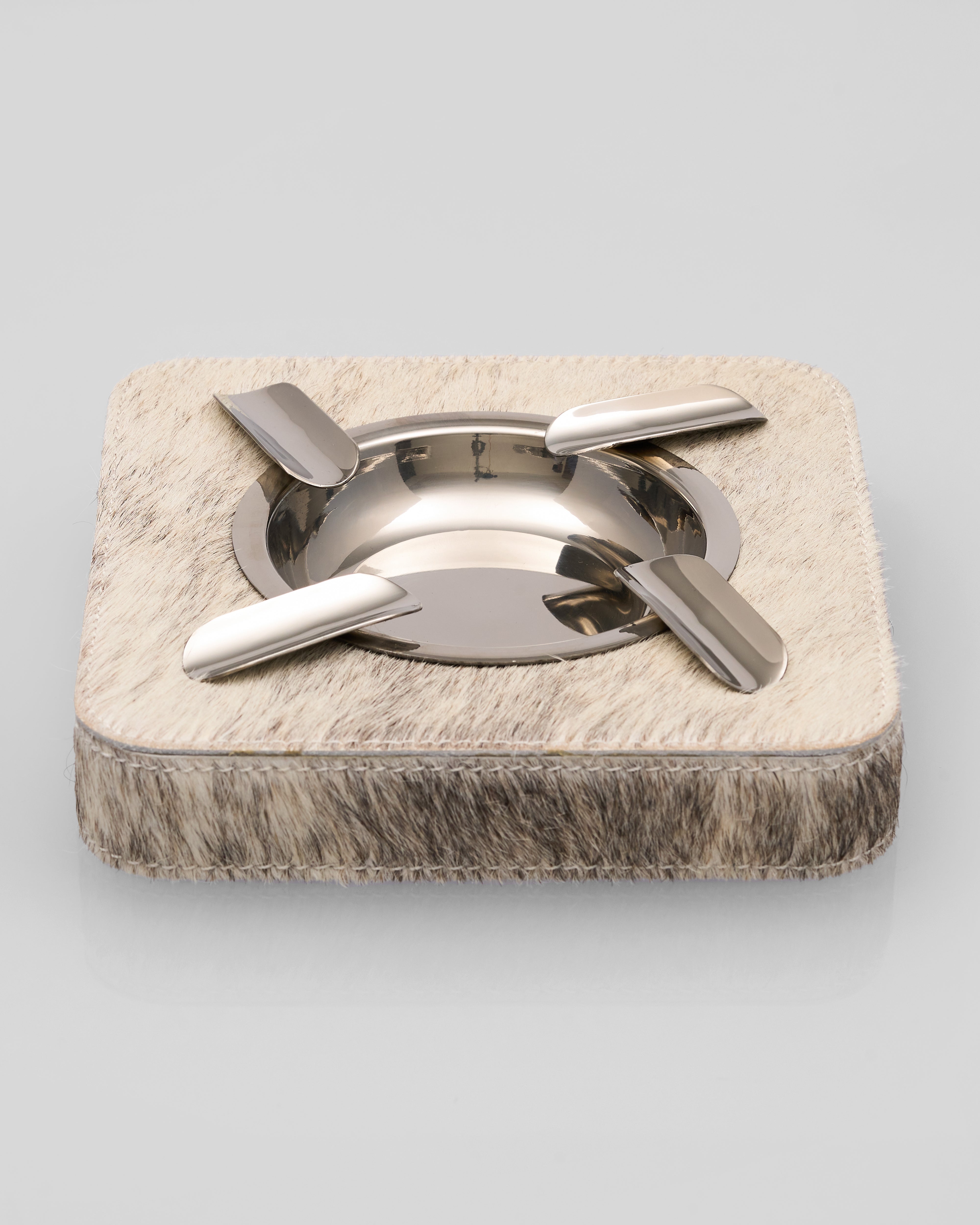 Metallic ashtray with natural horse hair like base on a light gray background