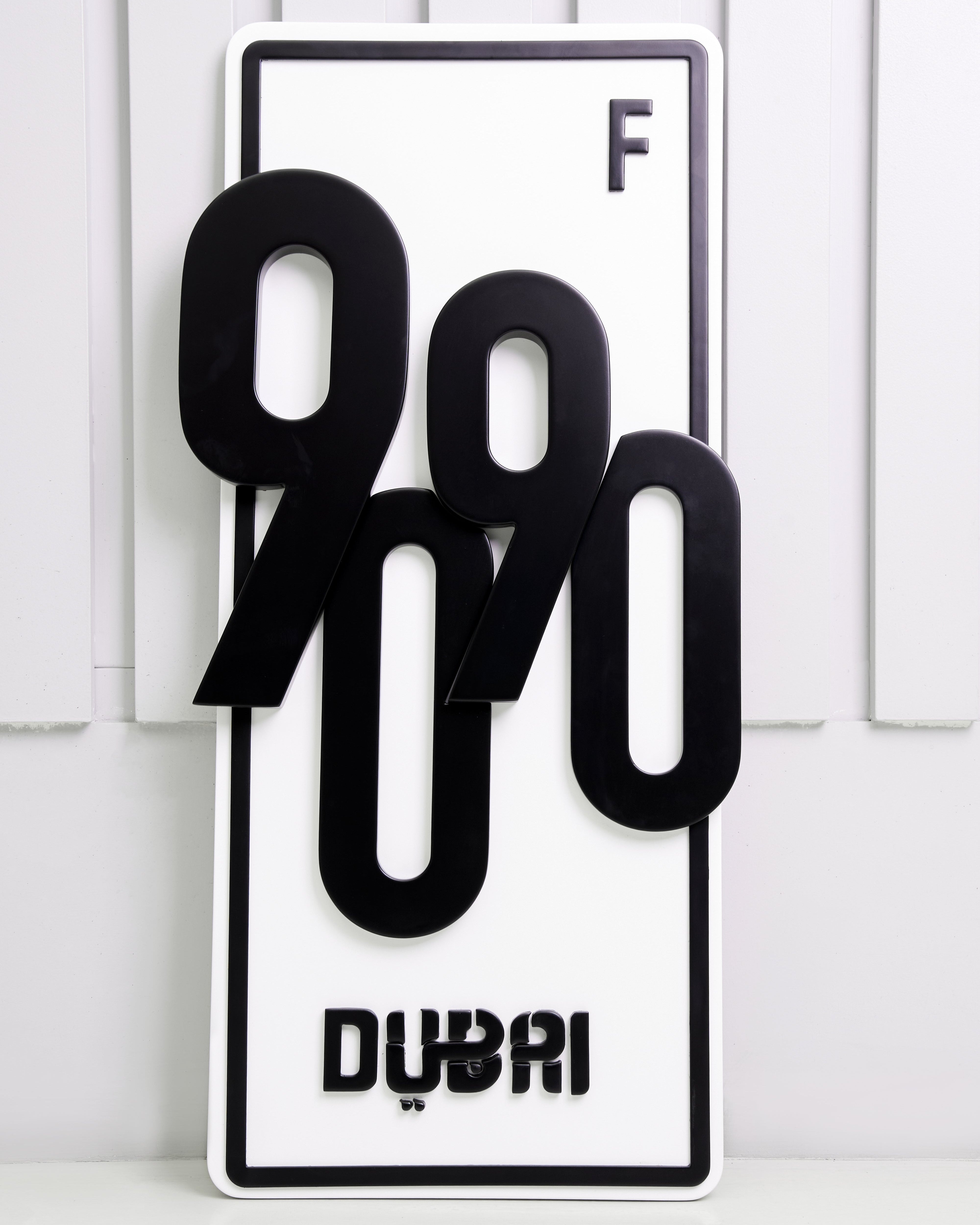 Black and white decorative plate with numbers and 'DUBAI' branding on a white background