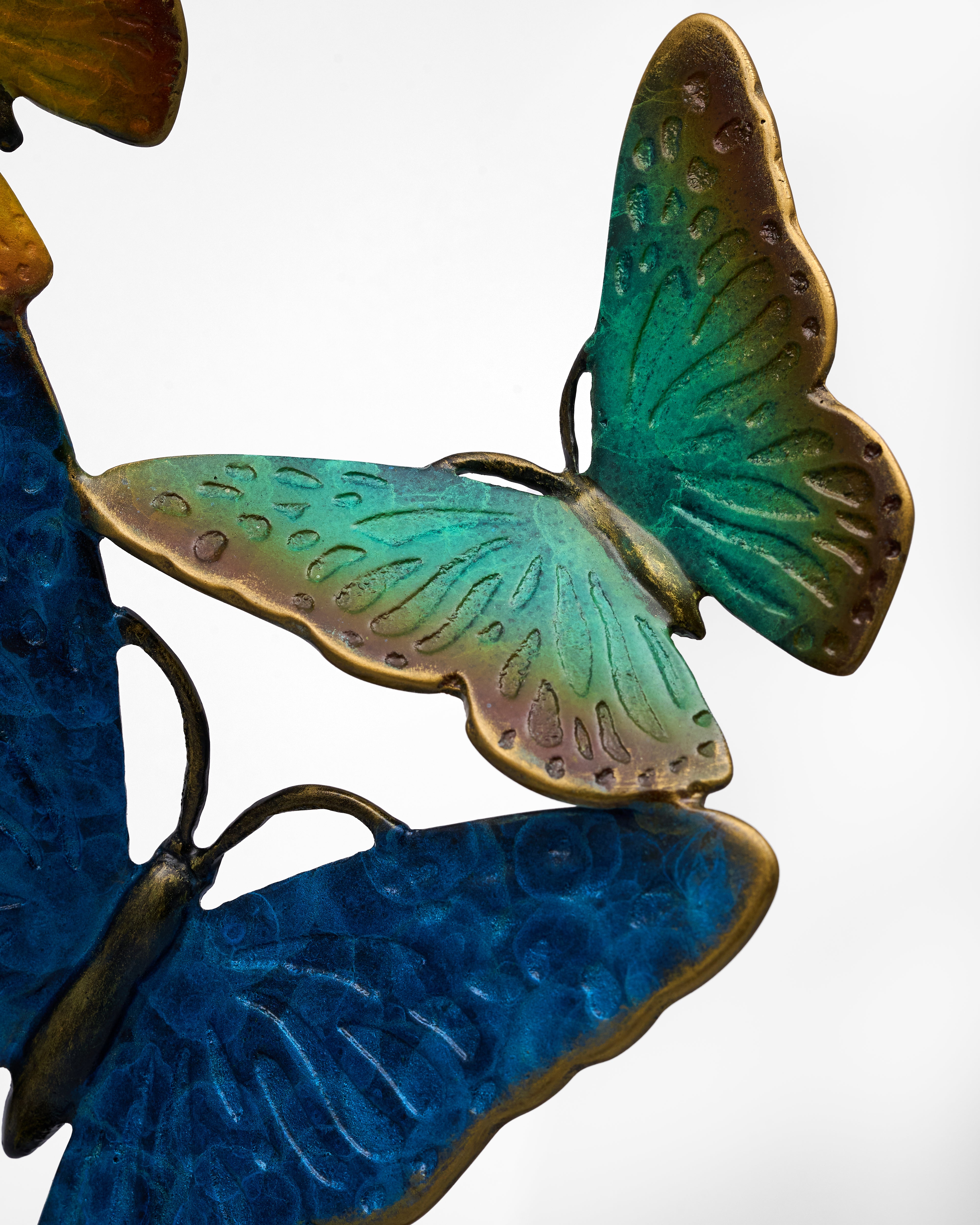 Metal butterfly sculpture with green and blue wings on a white background