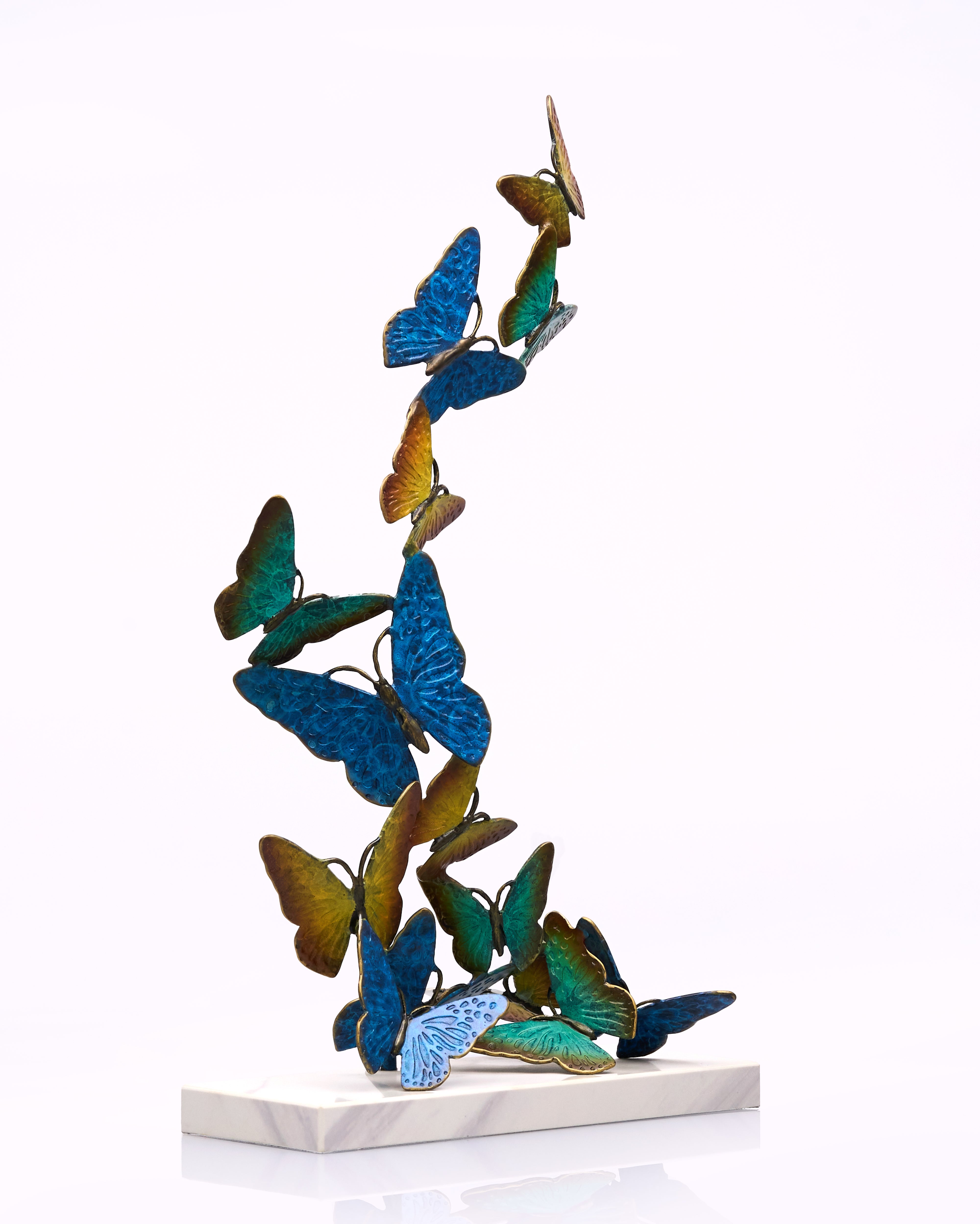 Metal butterfly sculpture on a white platform with a white background