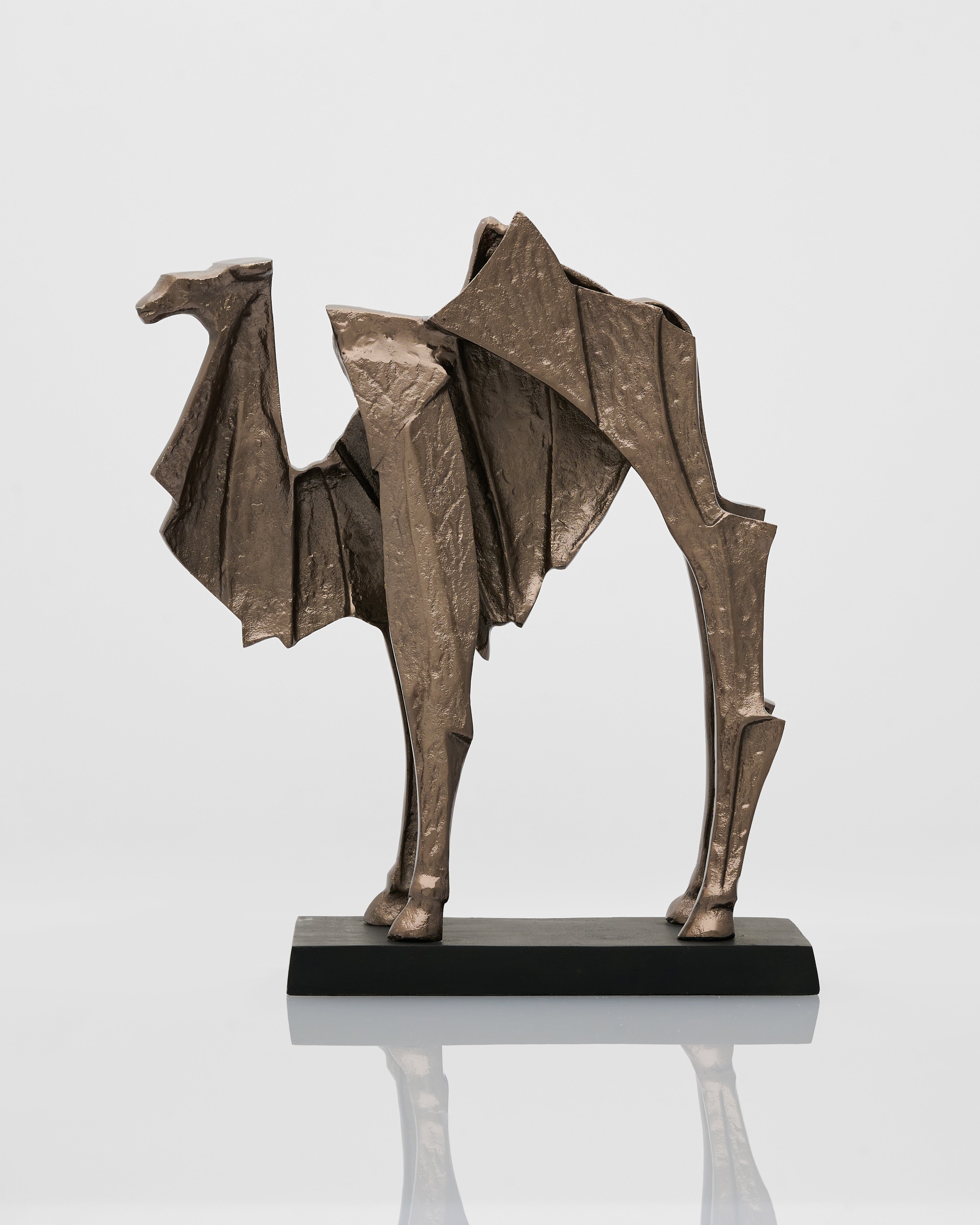 Bronze sculpture of a camel on a reflective surface with a light gray background