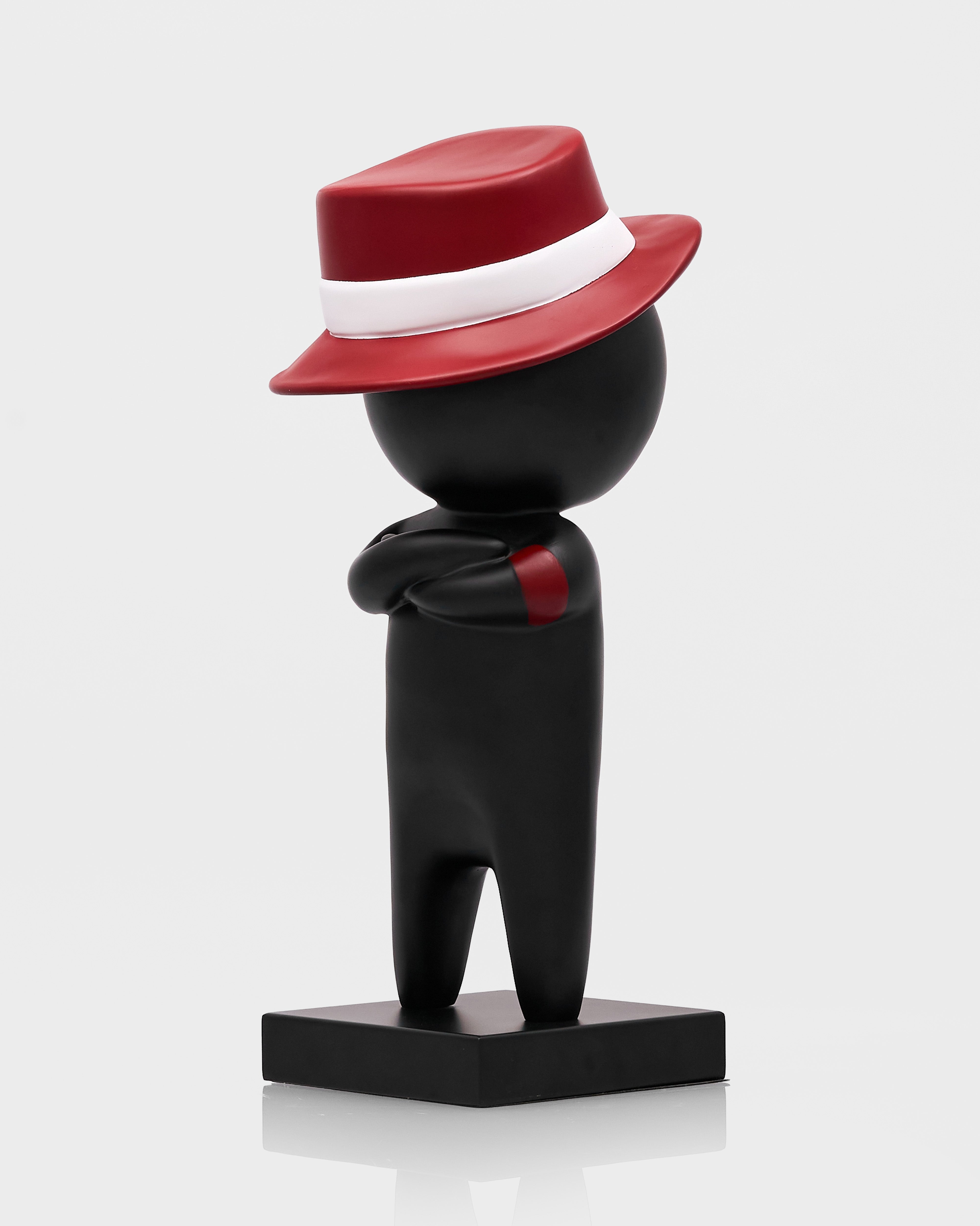 Black figurine with a red hat on a white background