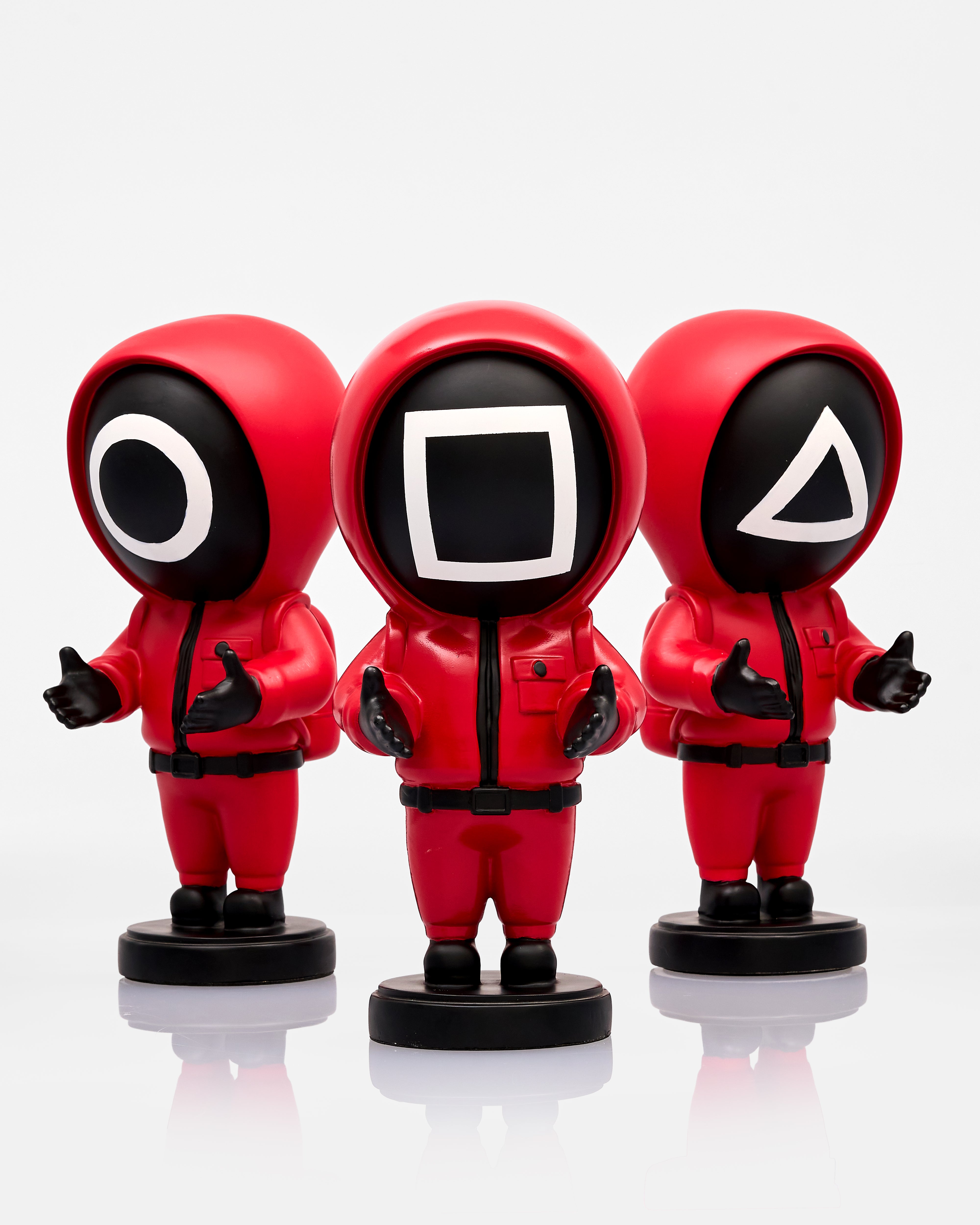 Three red superhero squid game figurines with unique face designs on a white background