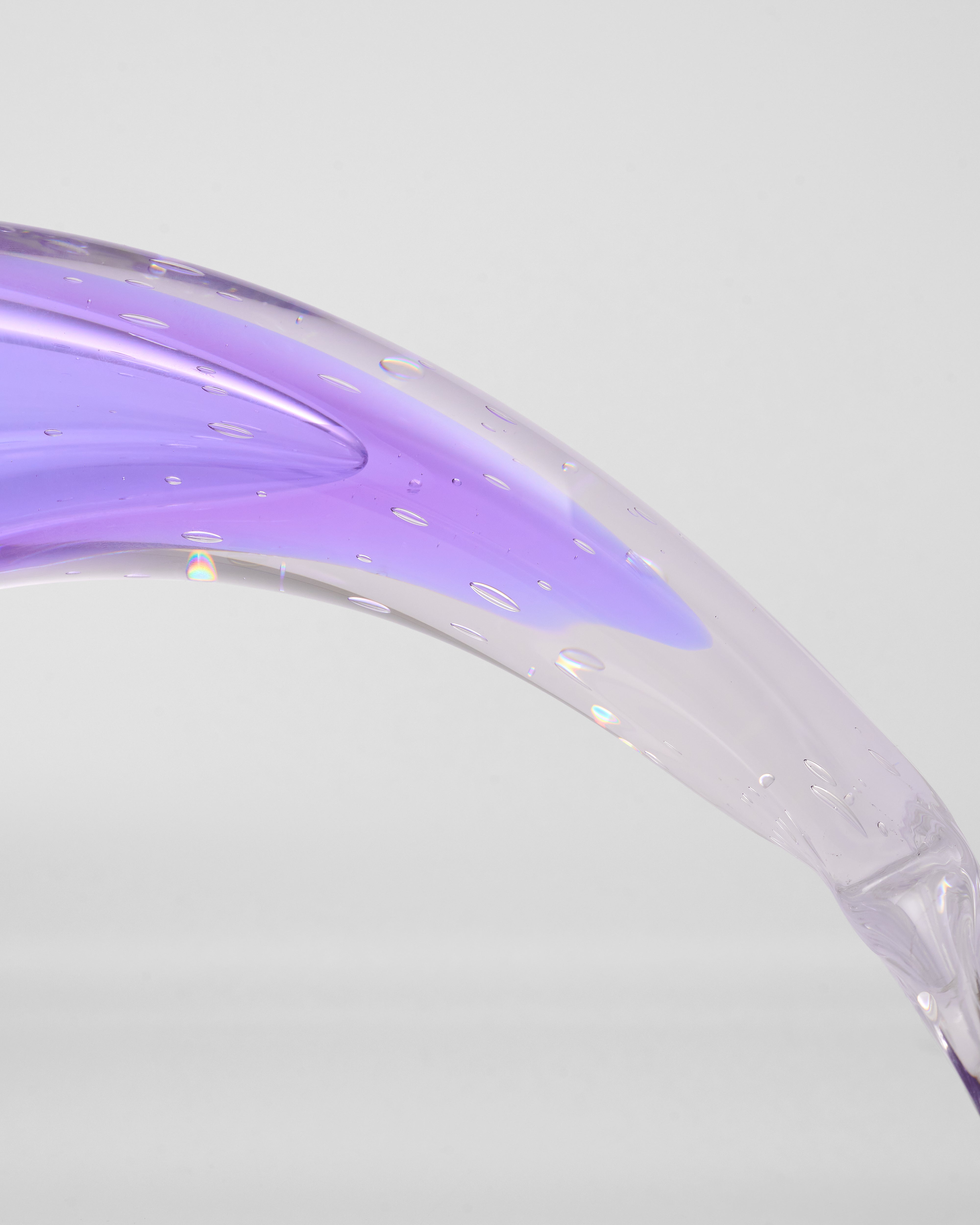 Close-up of a glass curved surface with a gradient from purple to clear on a light gray background