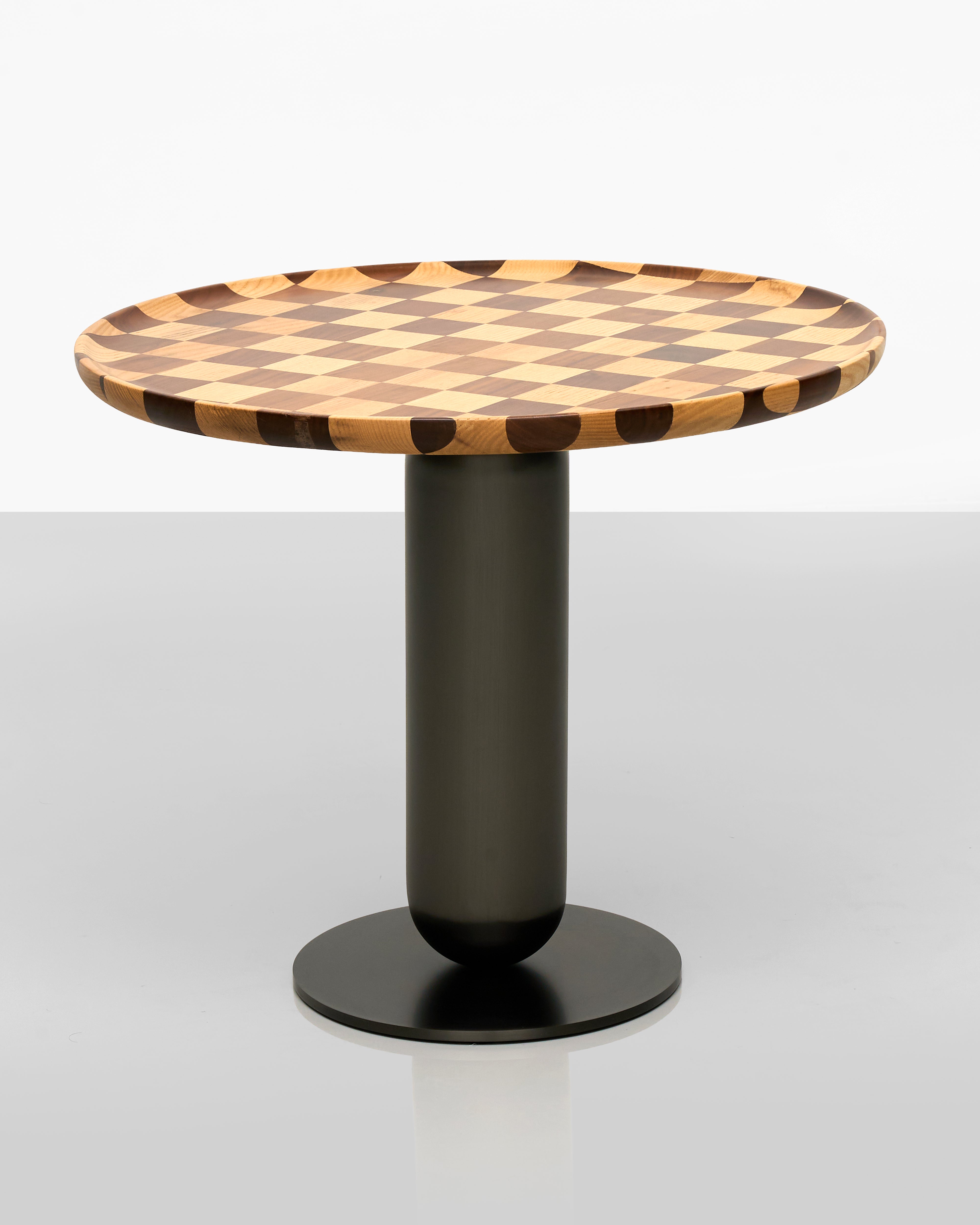 Round table with a checkered wooden top and black cylindrical base on a white background
