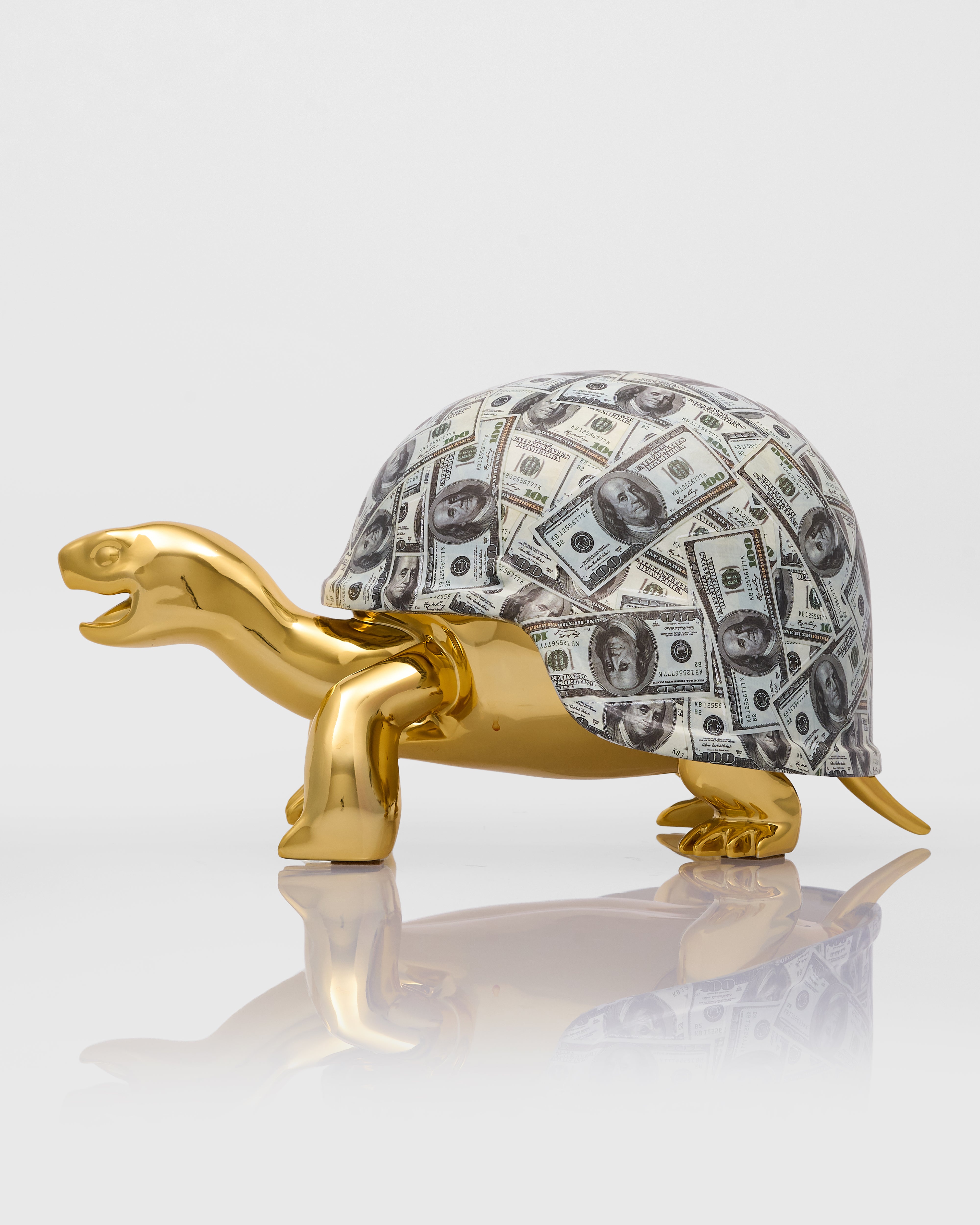 Gold turtle figurine with a shell made of dollar bills on a white background