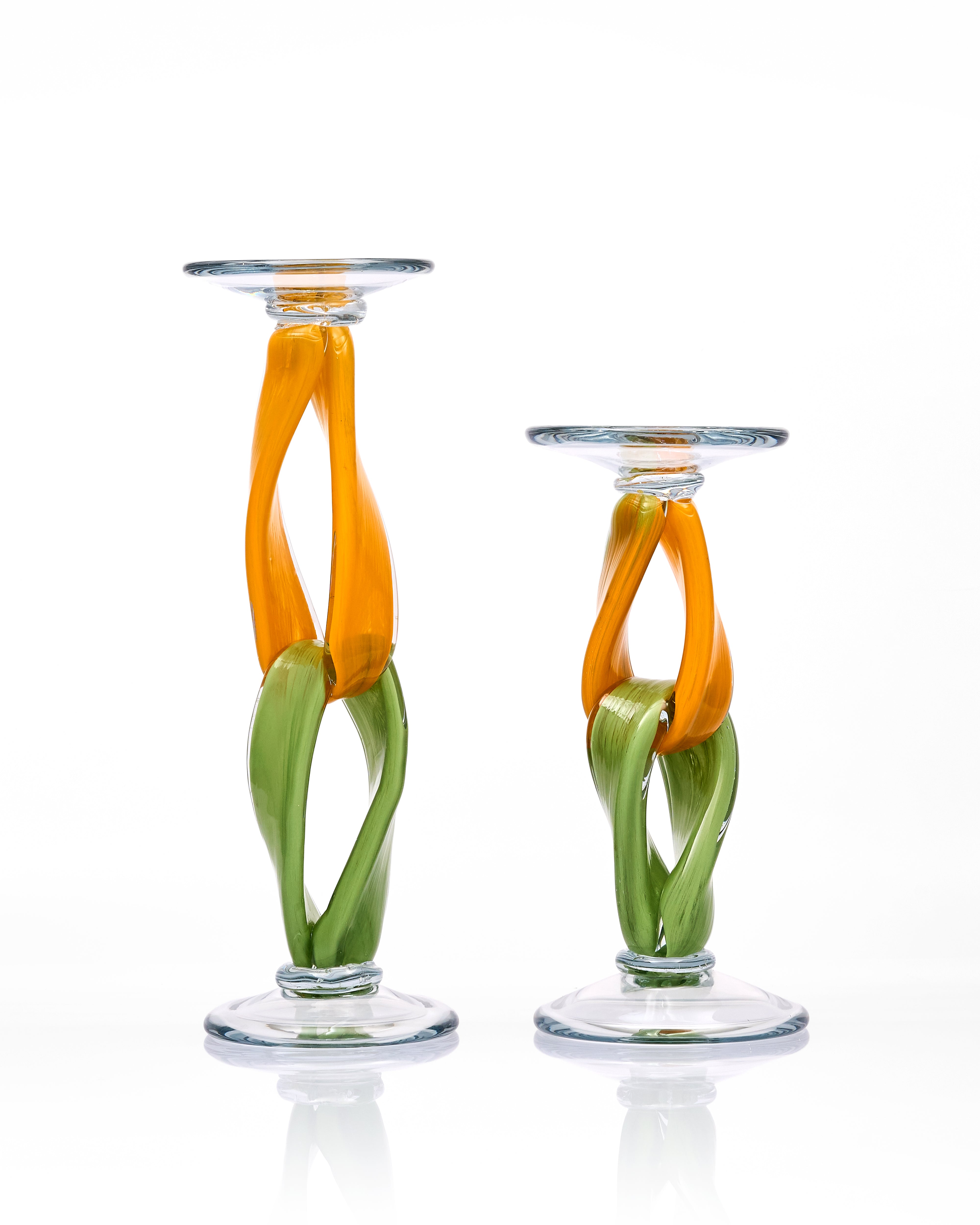 Two glass candle holders with orange and green design on a white background