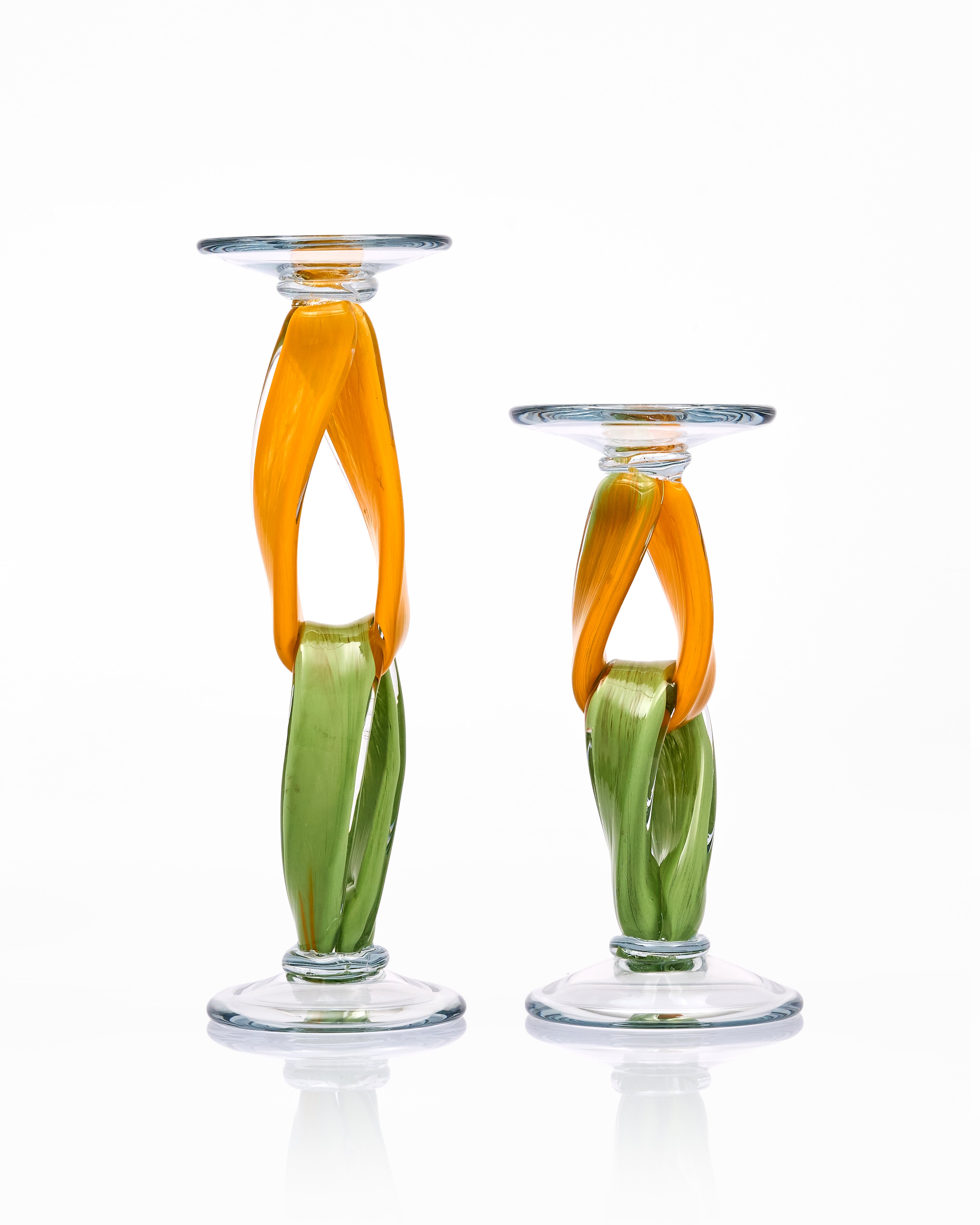 Two glass candle holders with orange and green design on a white background