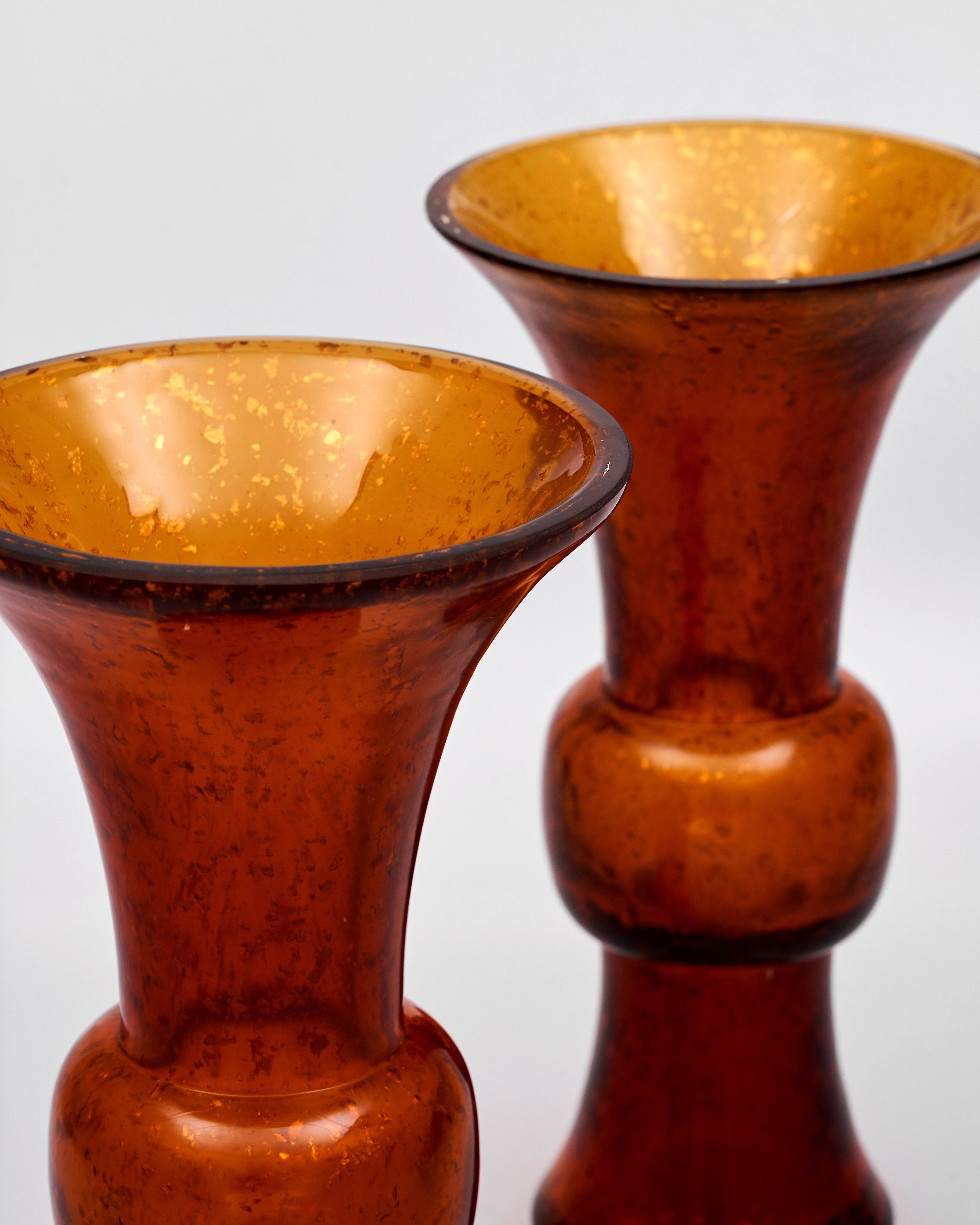 Two amber-colored glass vases on a light gray background