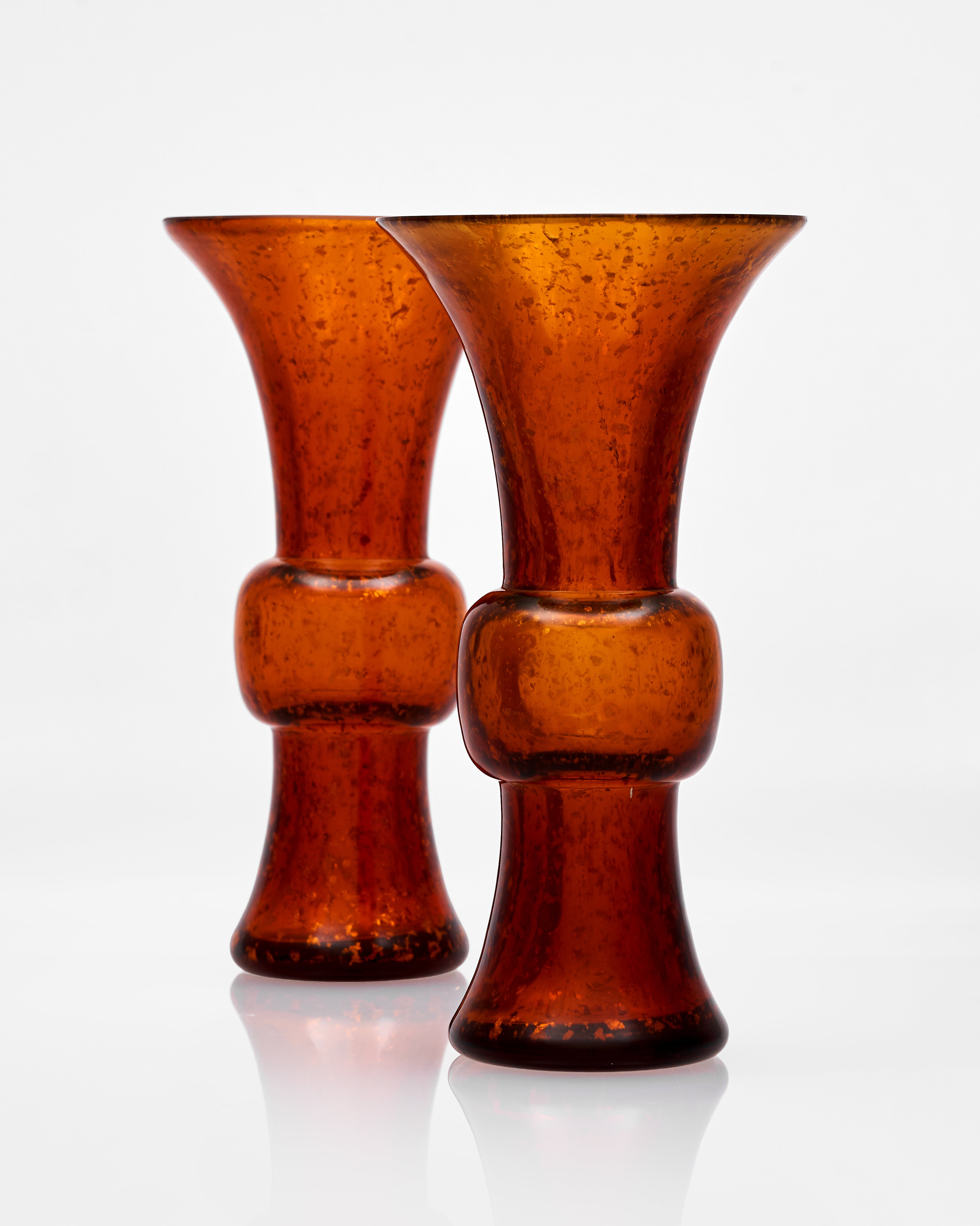 Two amber-colored glass vases on a white background