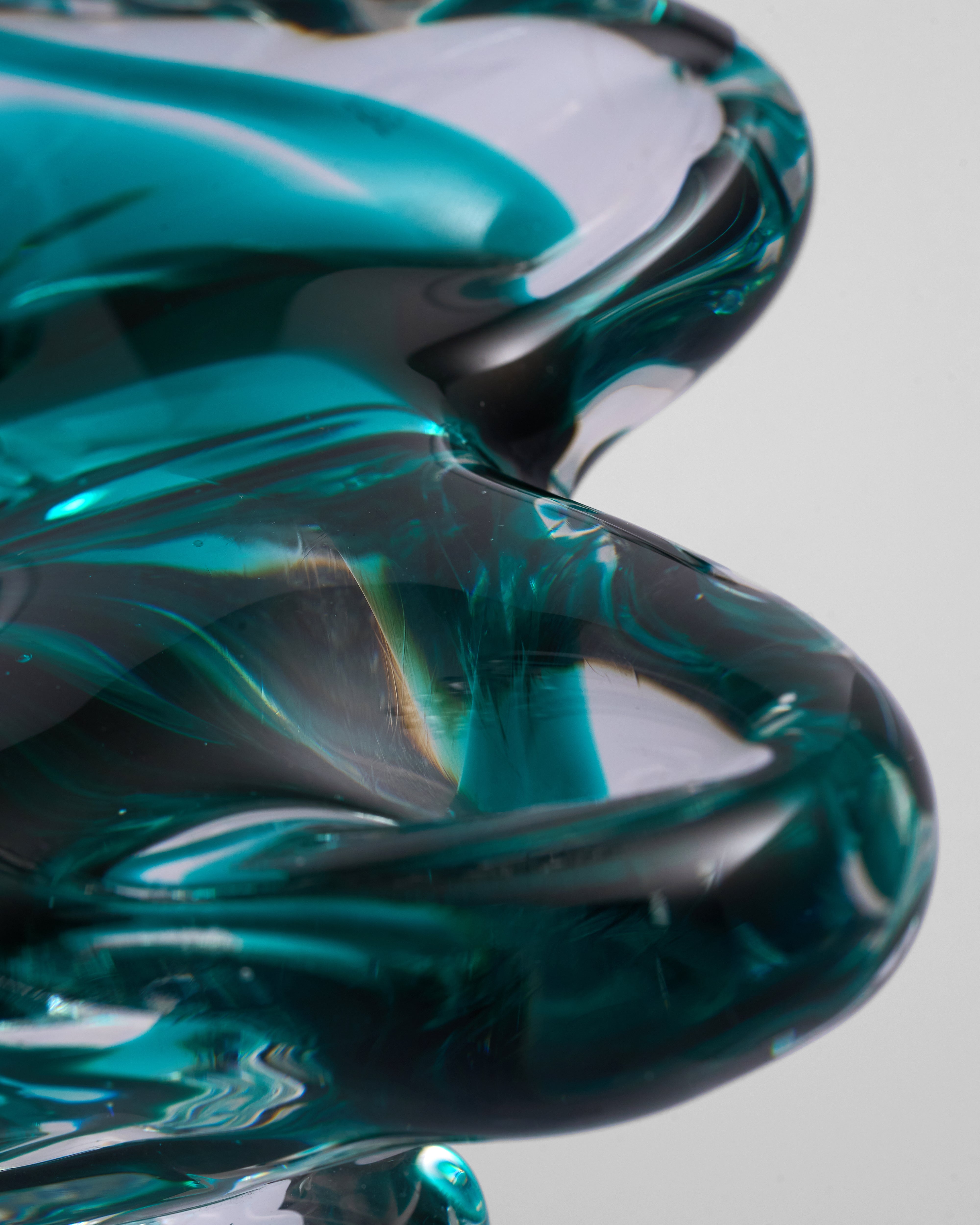 Close-up of a green and black glass sculpture on a gray background
