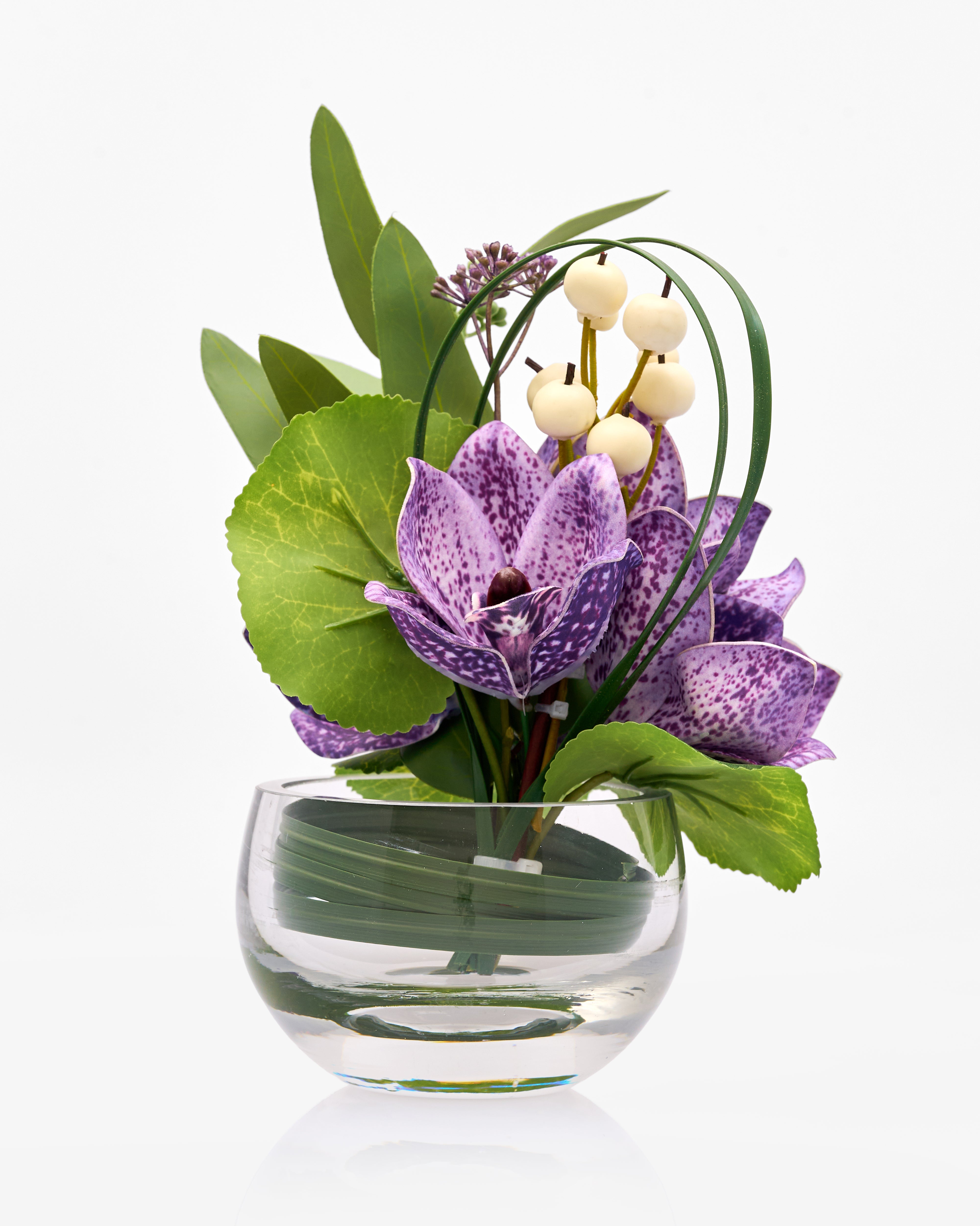 Purple orchid and green leaves in a clear glass vase on a white background