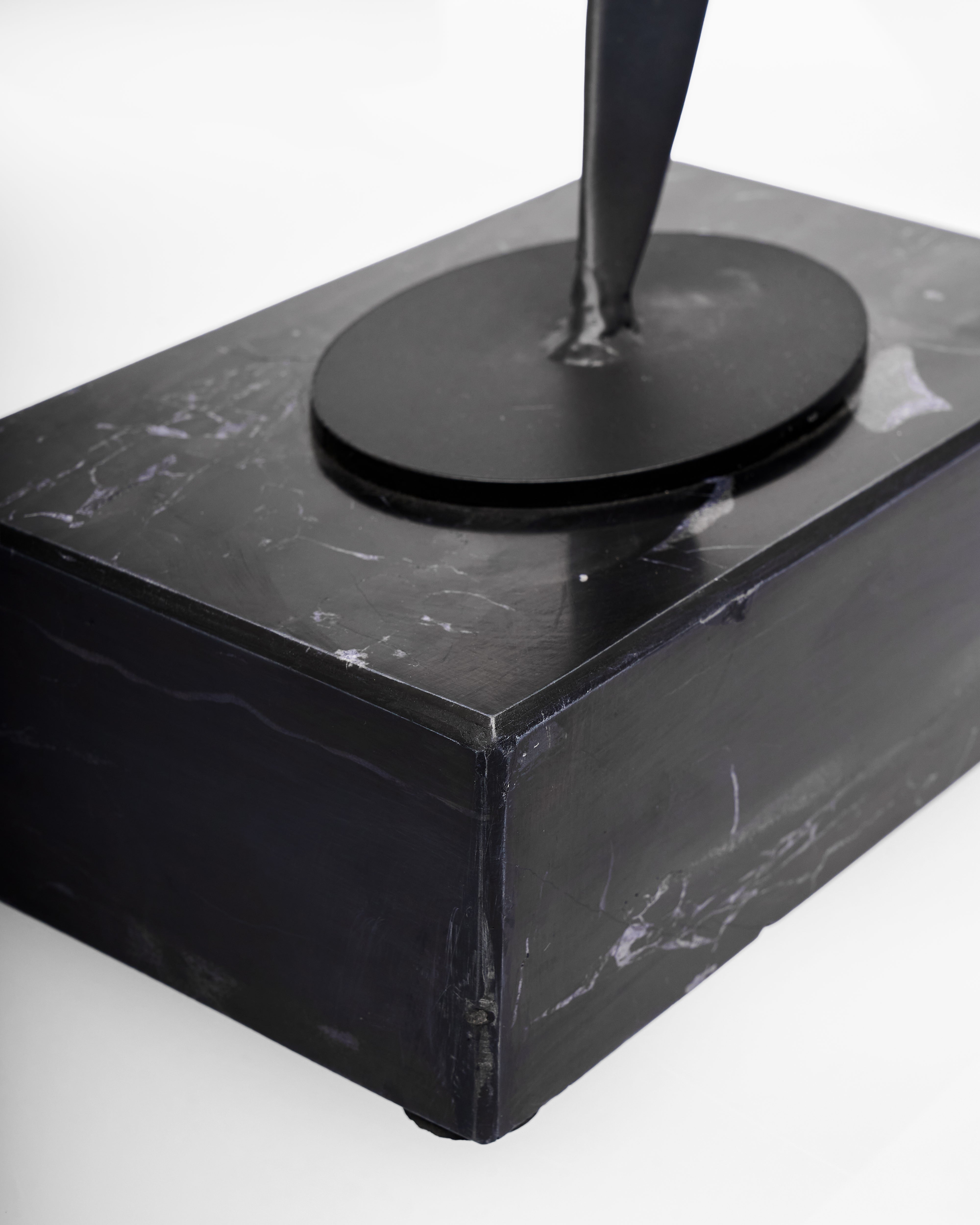 Black marble base with a cylindrical object on a white background