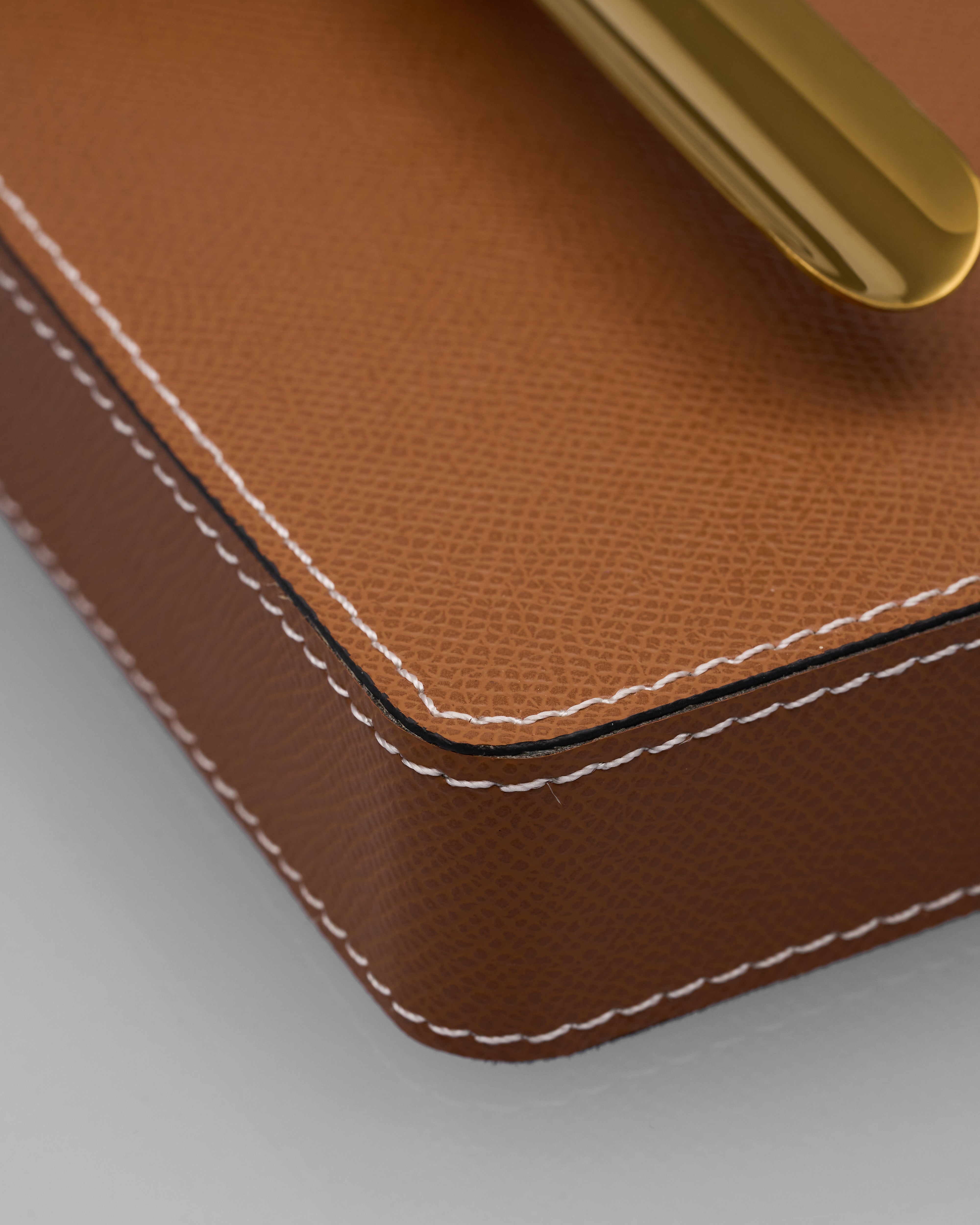 Close-up of a brown leather box of Gelo Leather Ashtray with a gold handle on a light gray background
