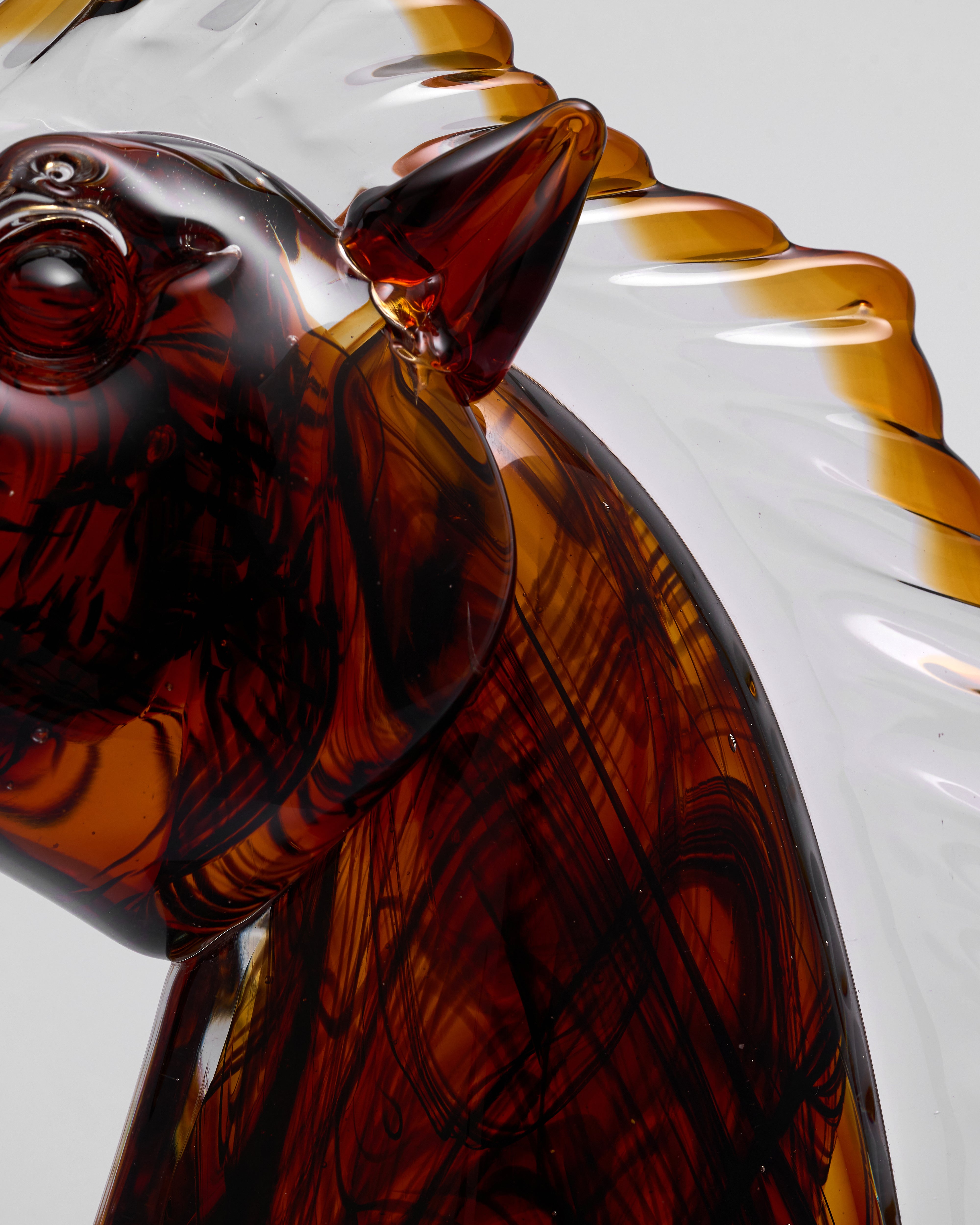 Close-up of a brown glass sculpture of a horse on a white background