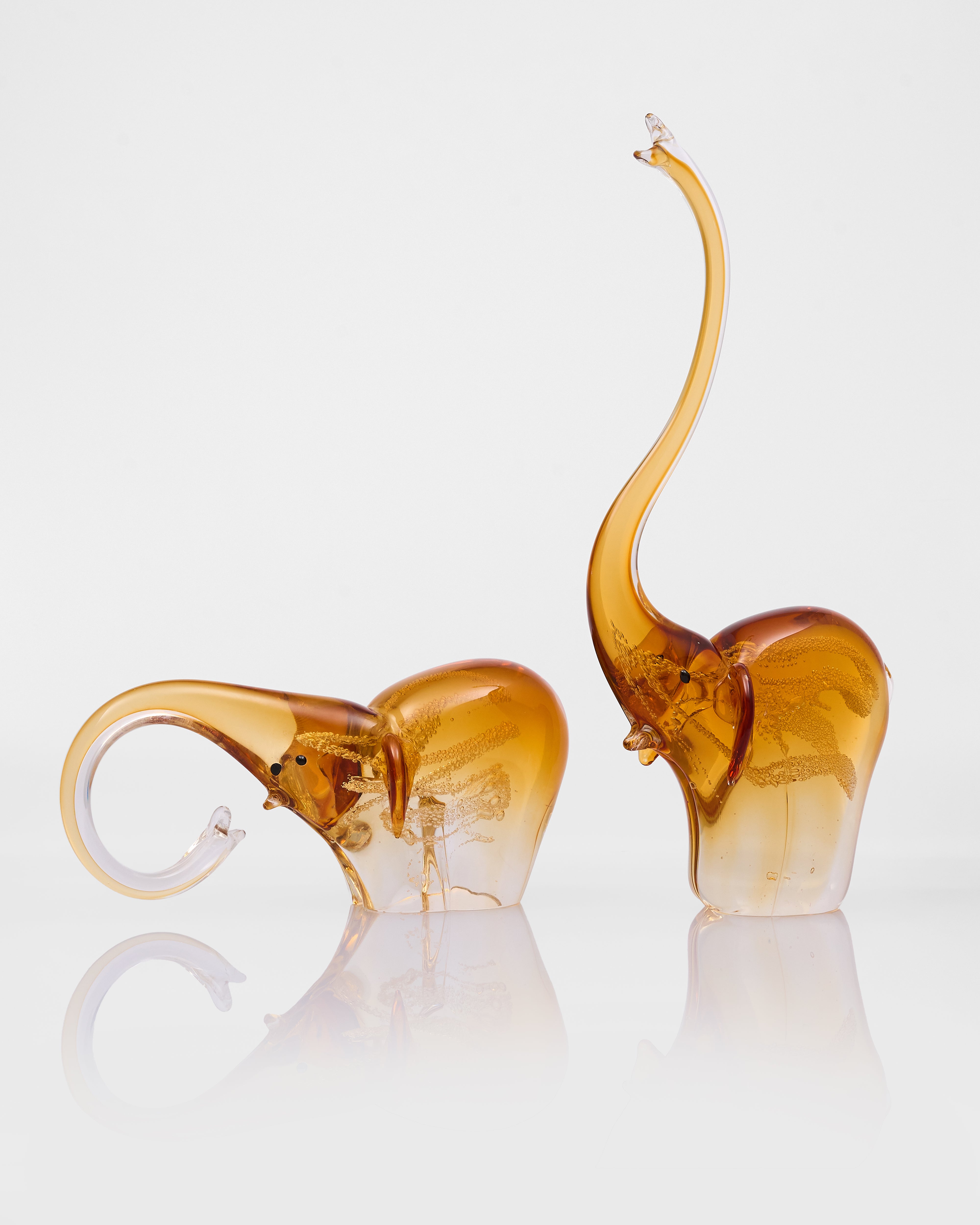 Two amber-colored glass elephants on a white background