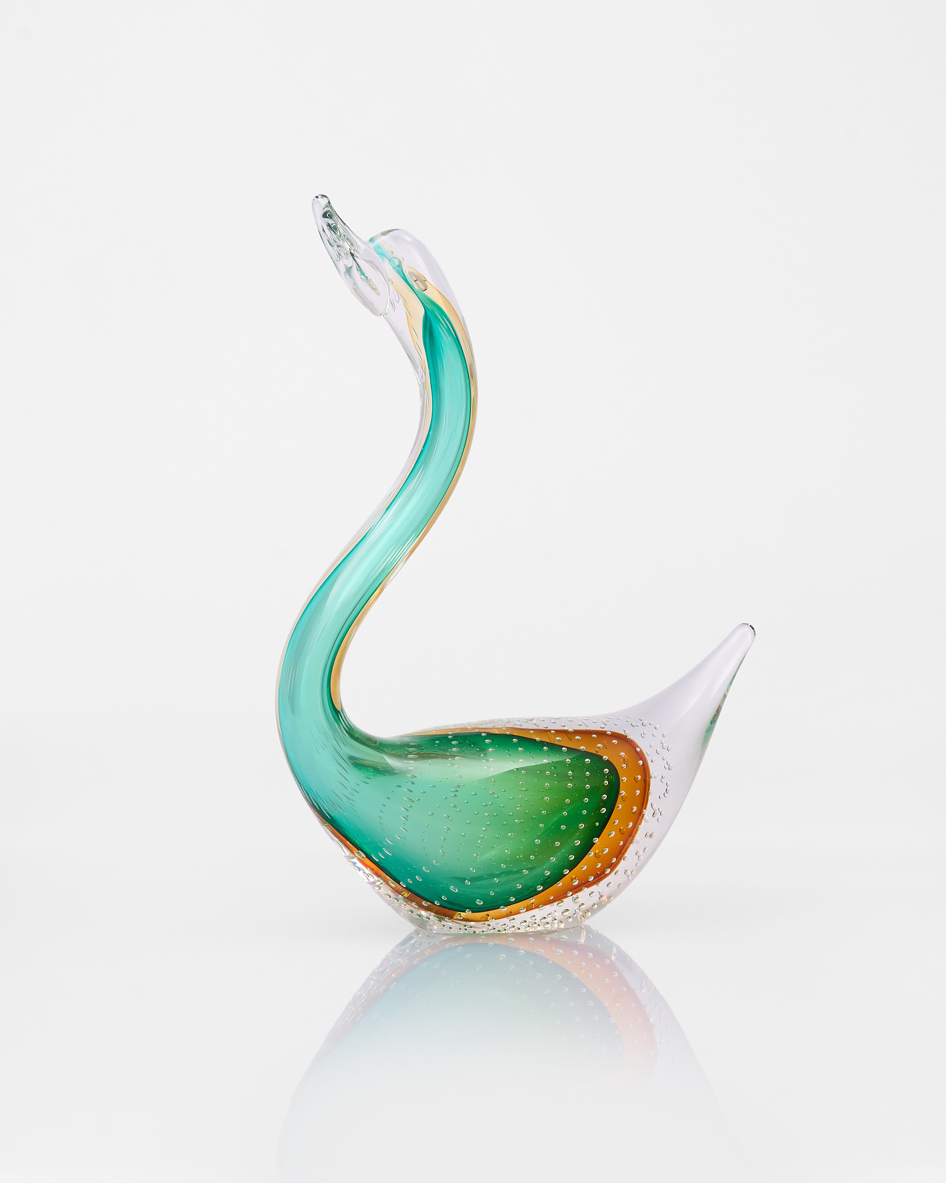 Glass swan sculpture with green and gold colors on a white background