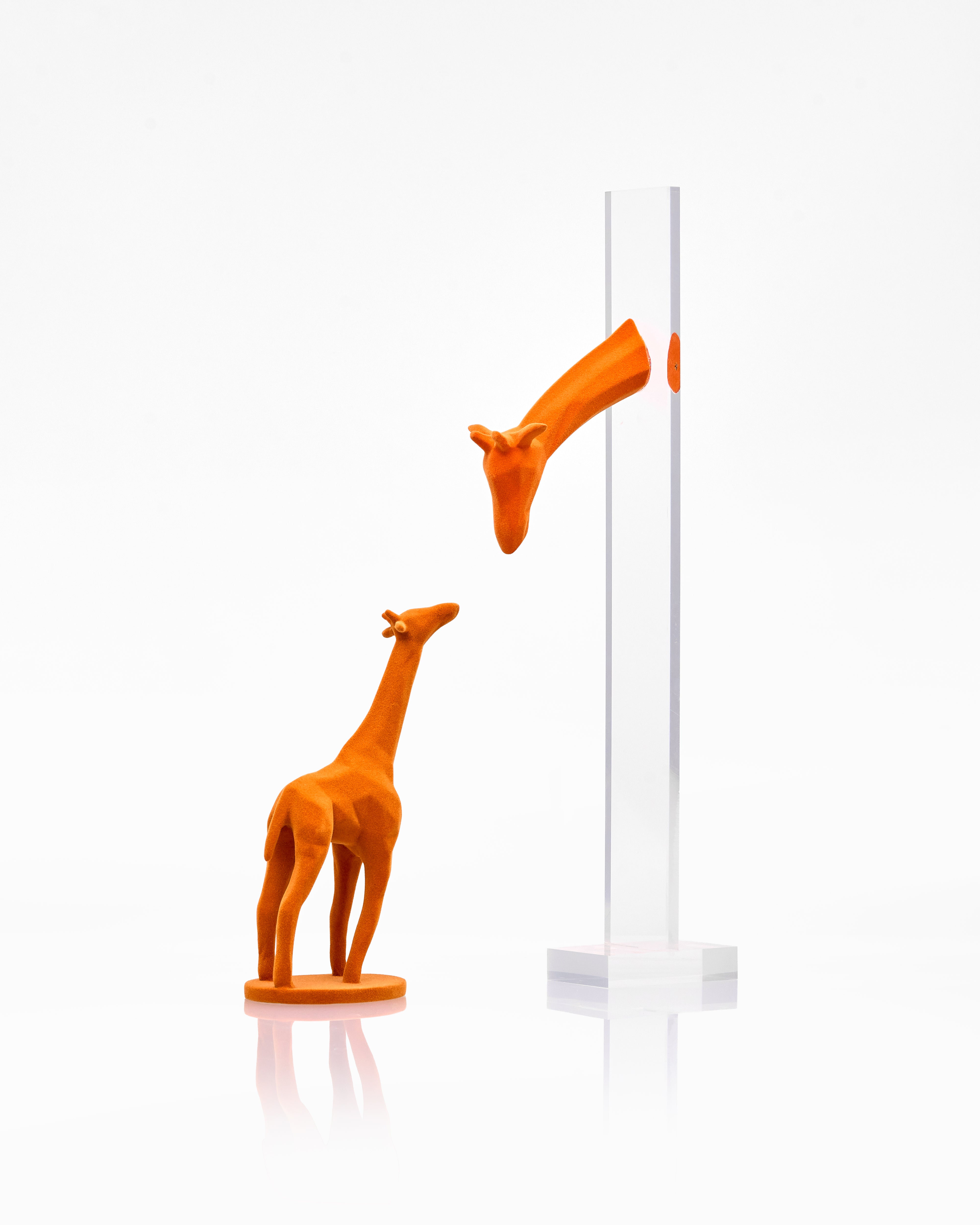 Two orange giraffe figurines interacting with a white pole on a white background