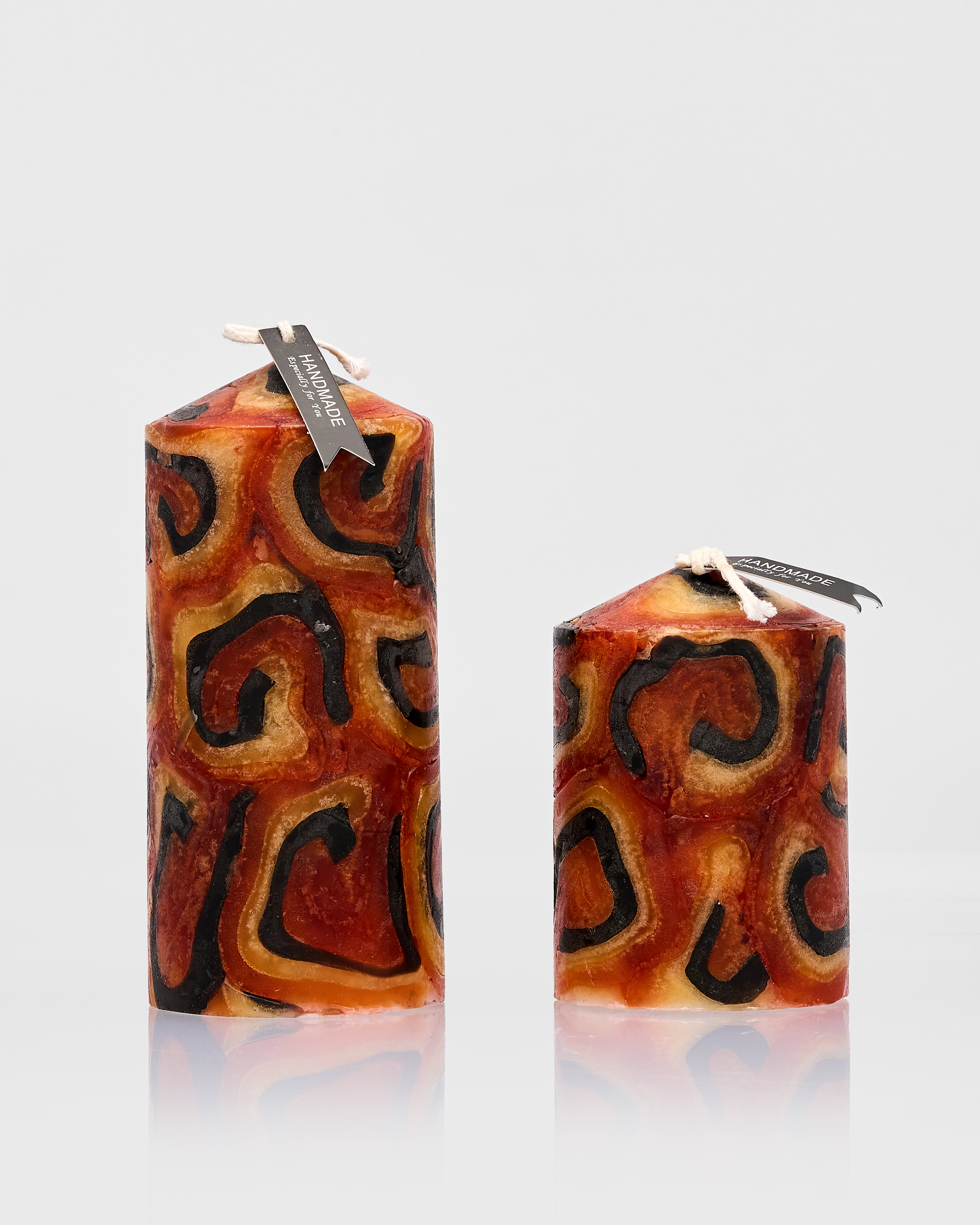 Two patterned candles with decorative swirls on a white background