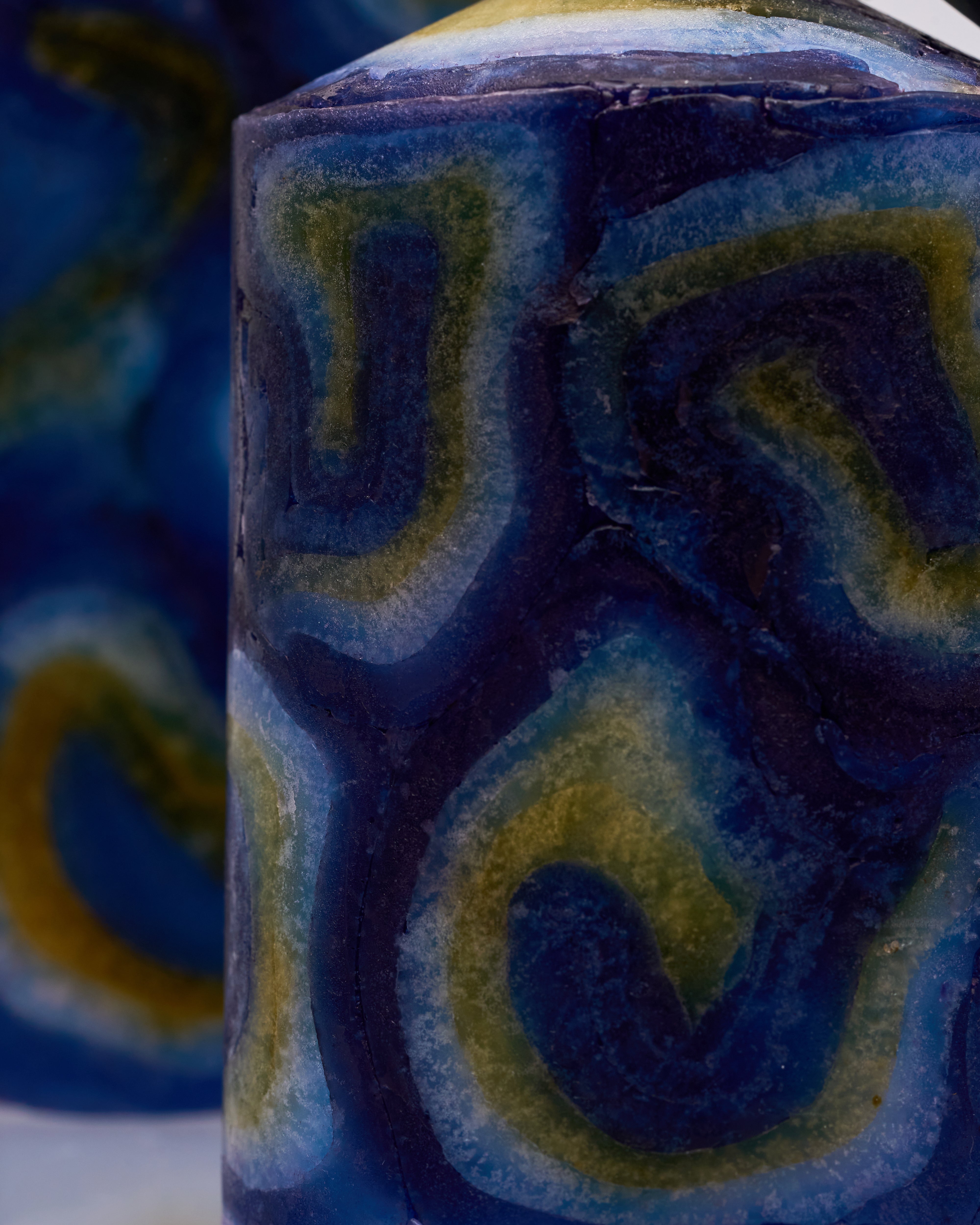 Close-up of a wax candle with blue and green decorative patterns