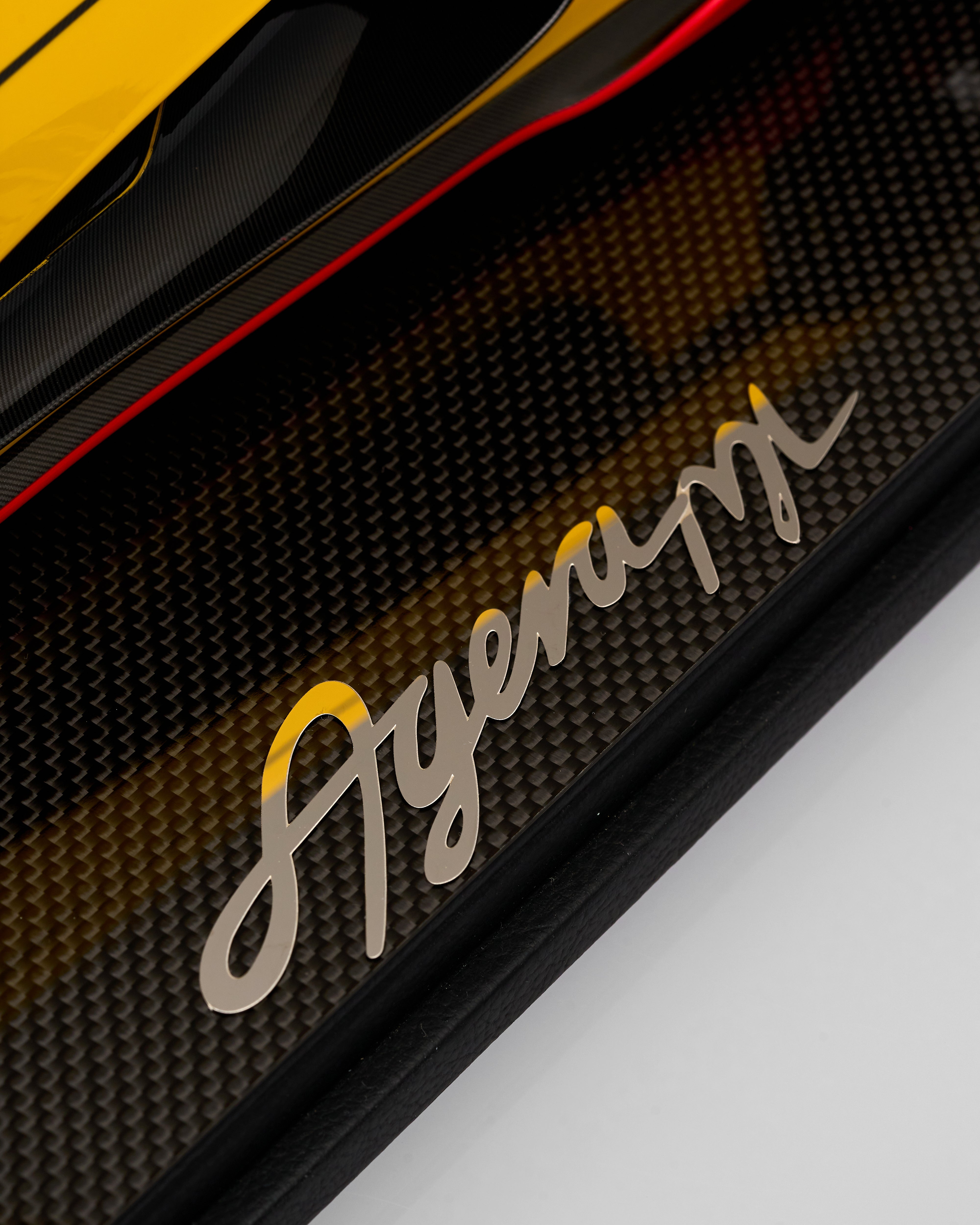 Close-up of a car grille with 'Agera' branding on a dark background