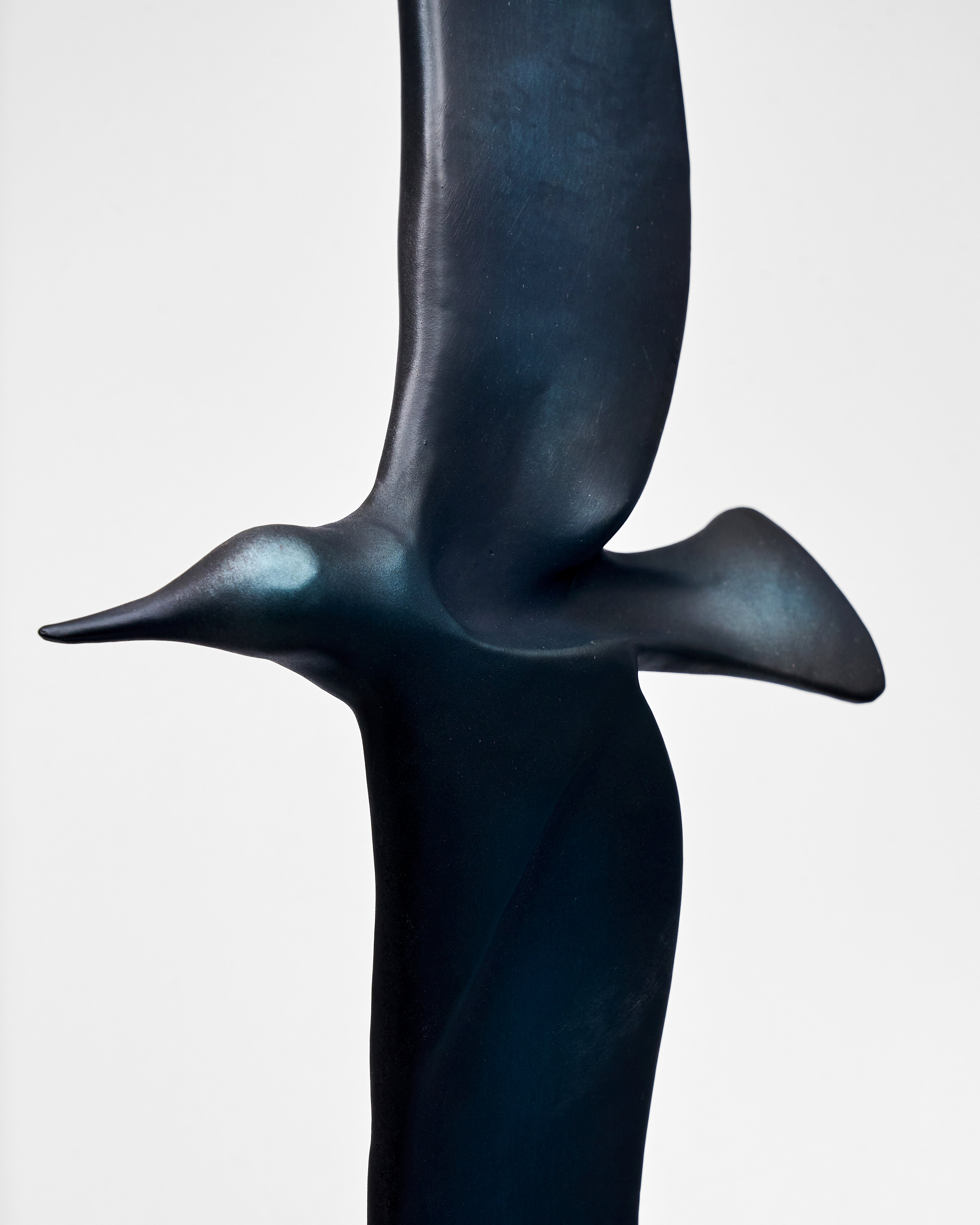 Bronze sculpture of a bird in flight on a white background