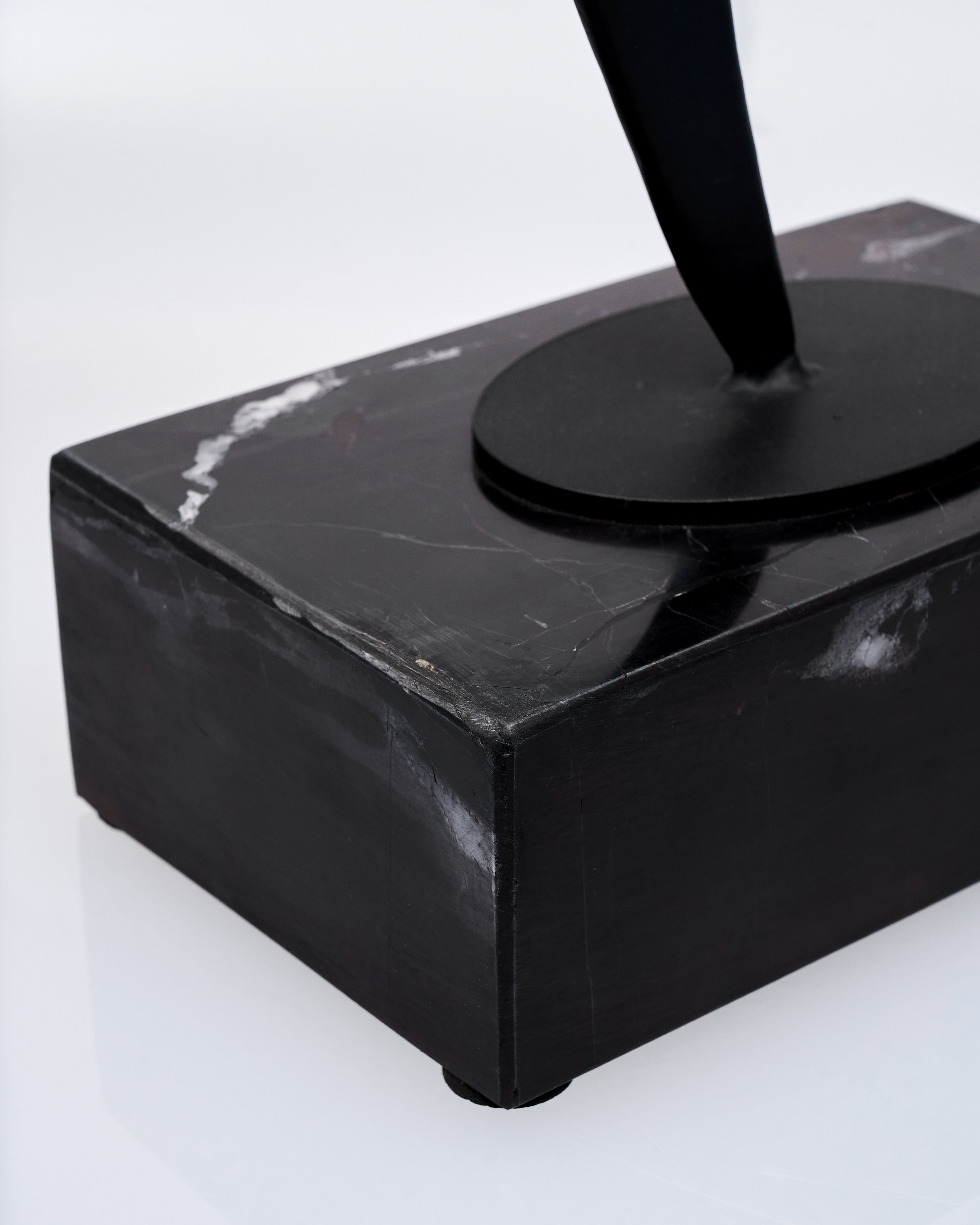 Black marble object with a cylindrical component on a white background