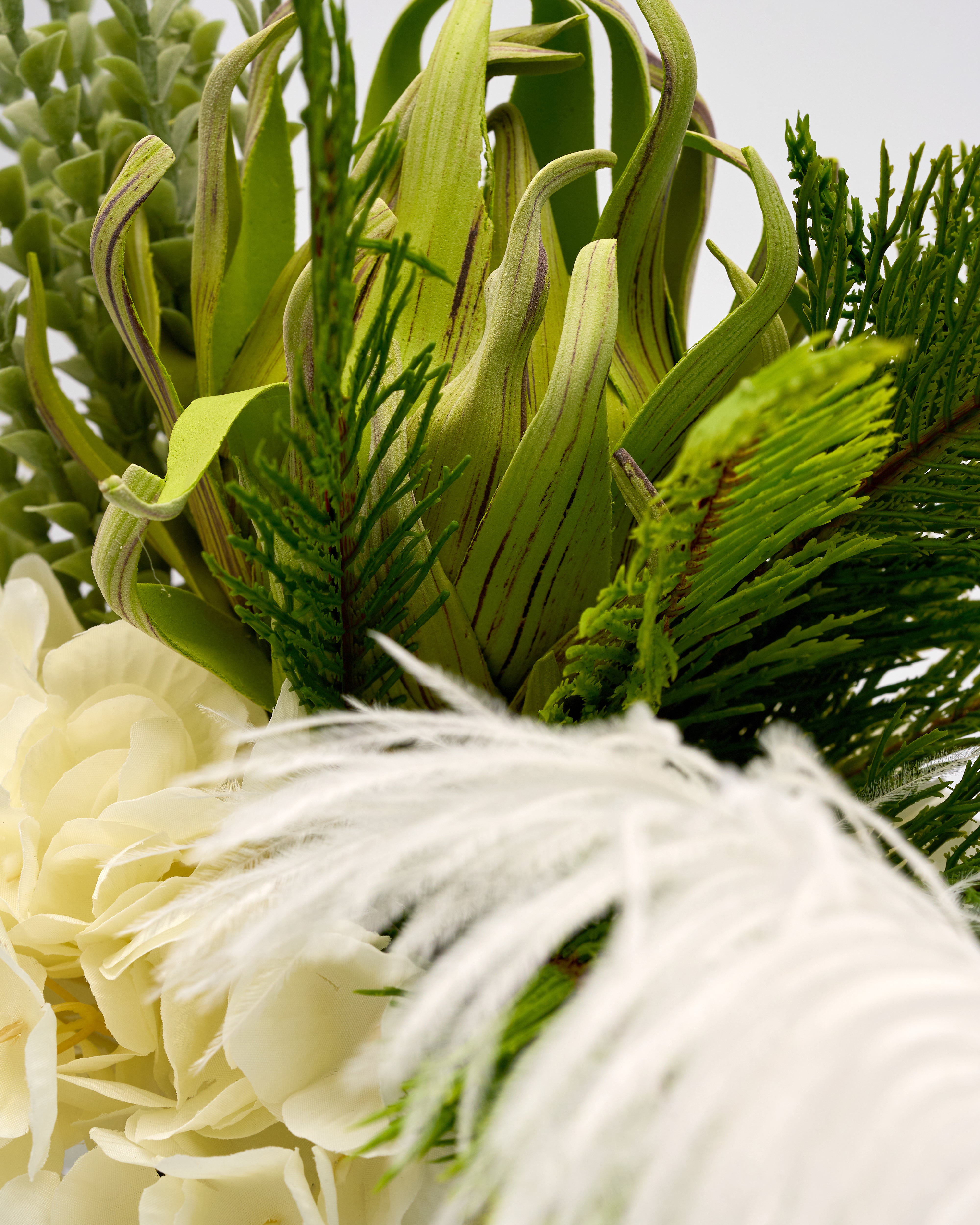 Close-up of a floral arrangement with green leaves and white flowers.