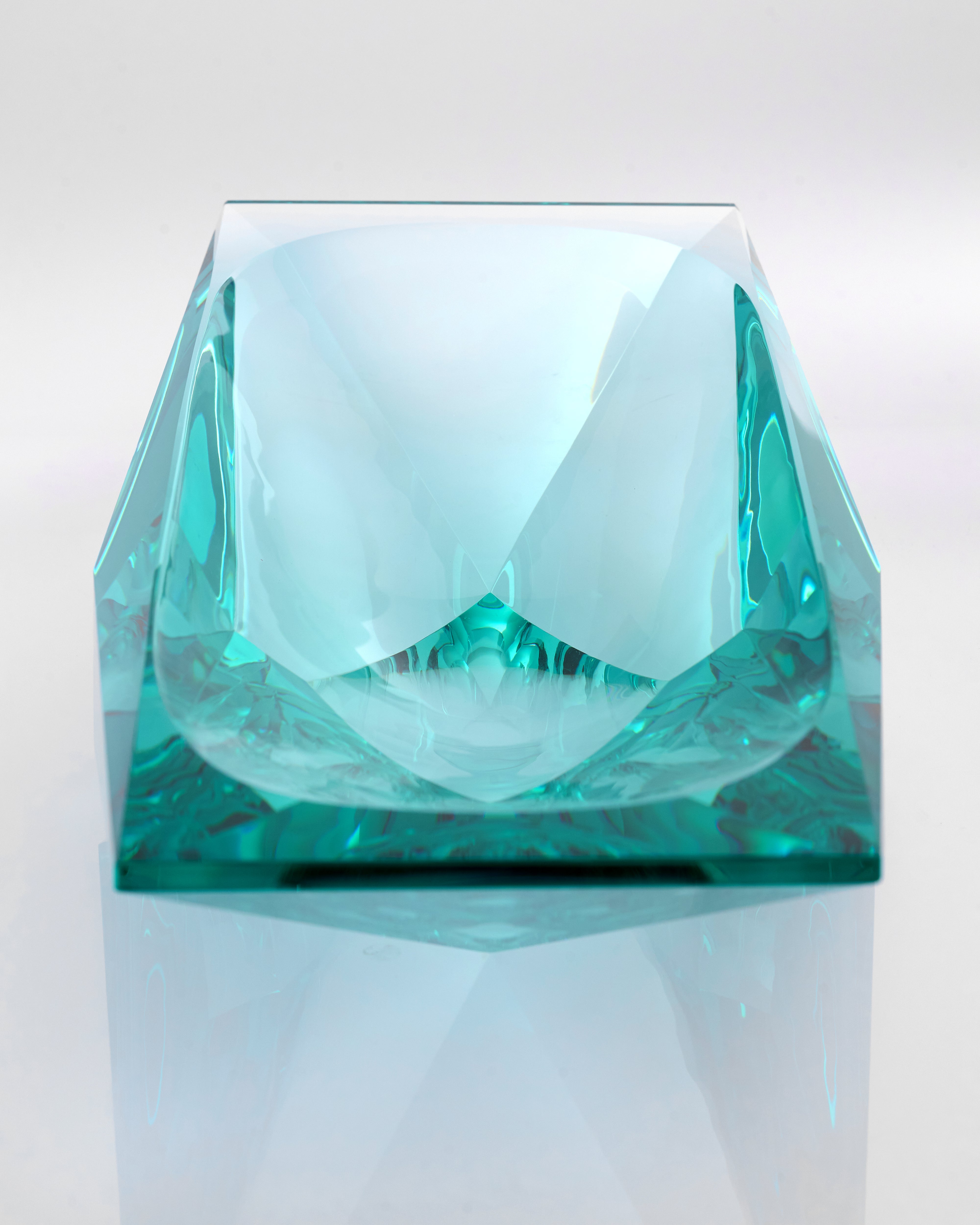 Teal glass sculpture on a white background