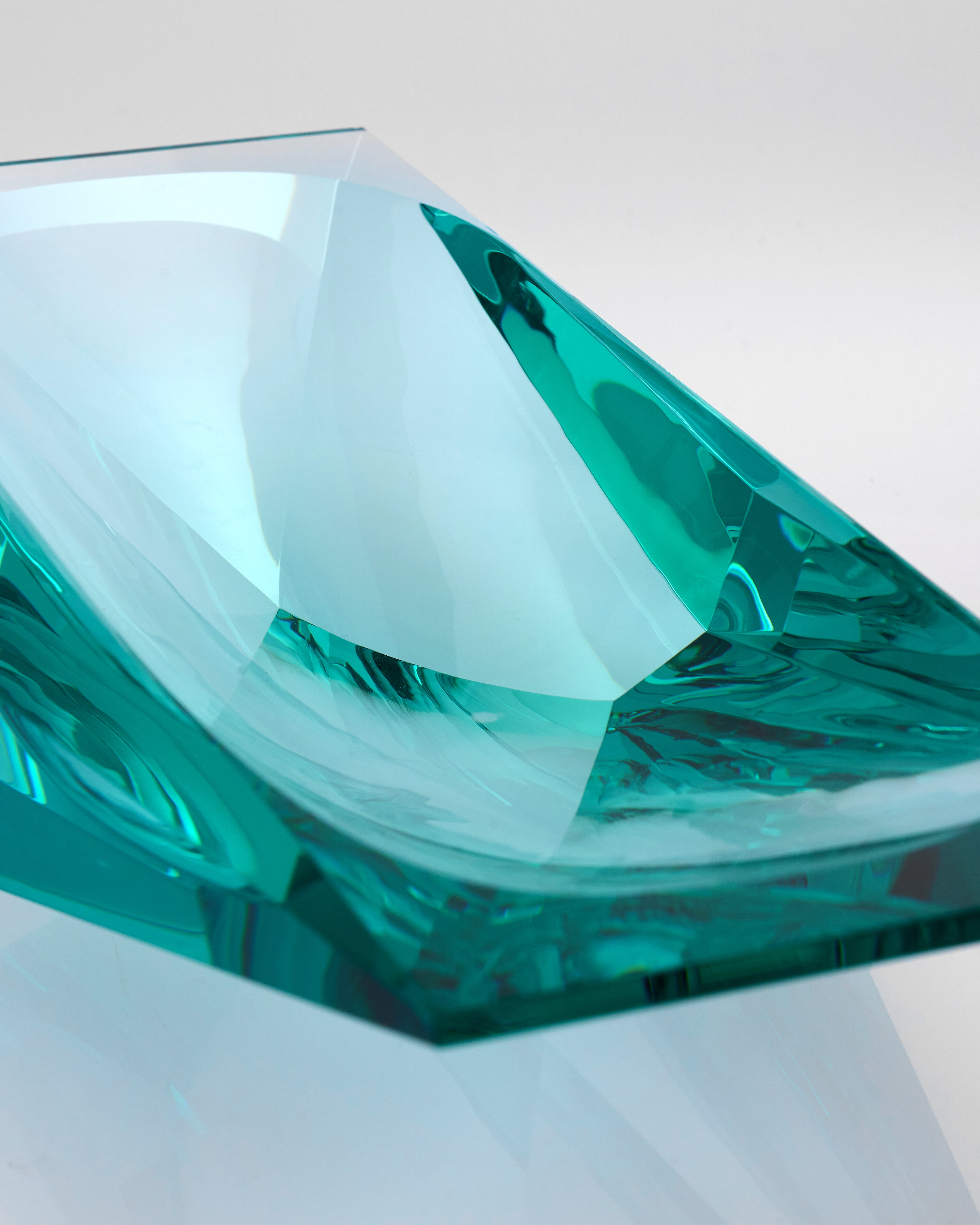 Teal glass object on a light gray background