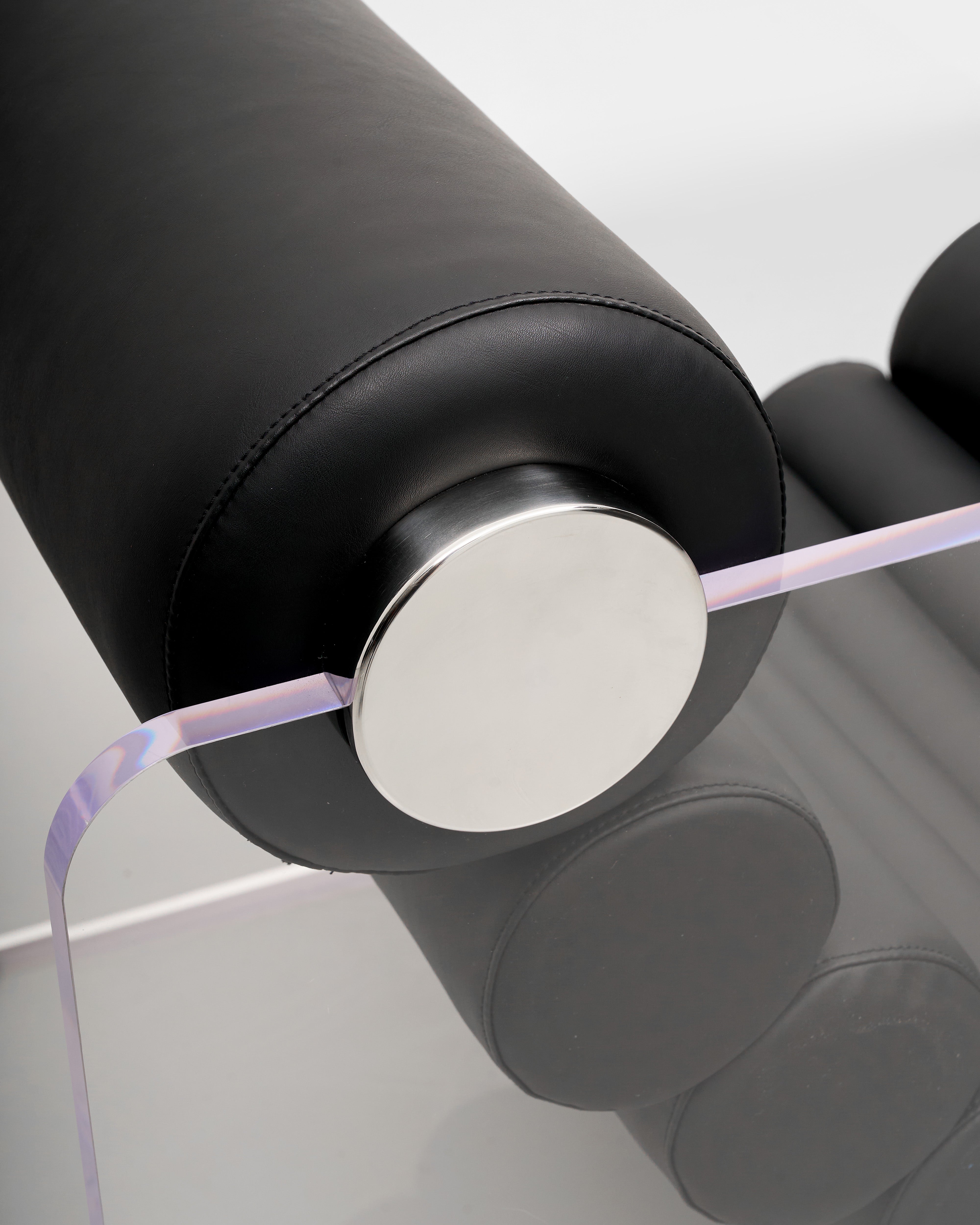 Close-up of a Lucent Acrylic & Black Leather Accent Jake Chair with black handle and silver disc on a white background