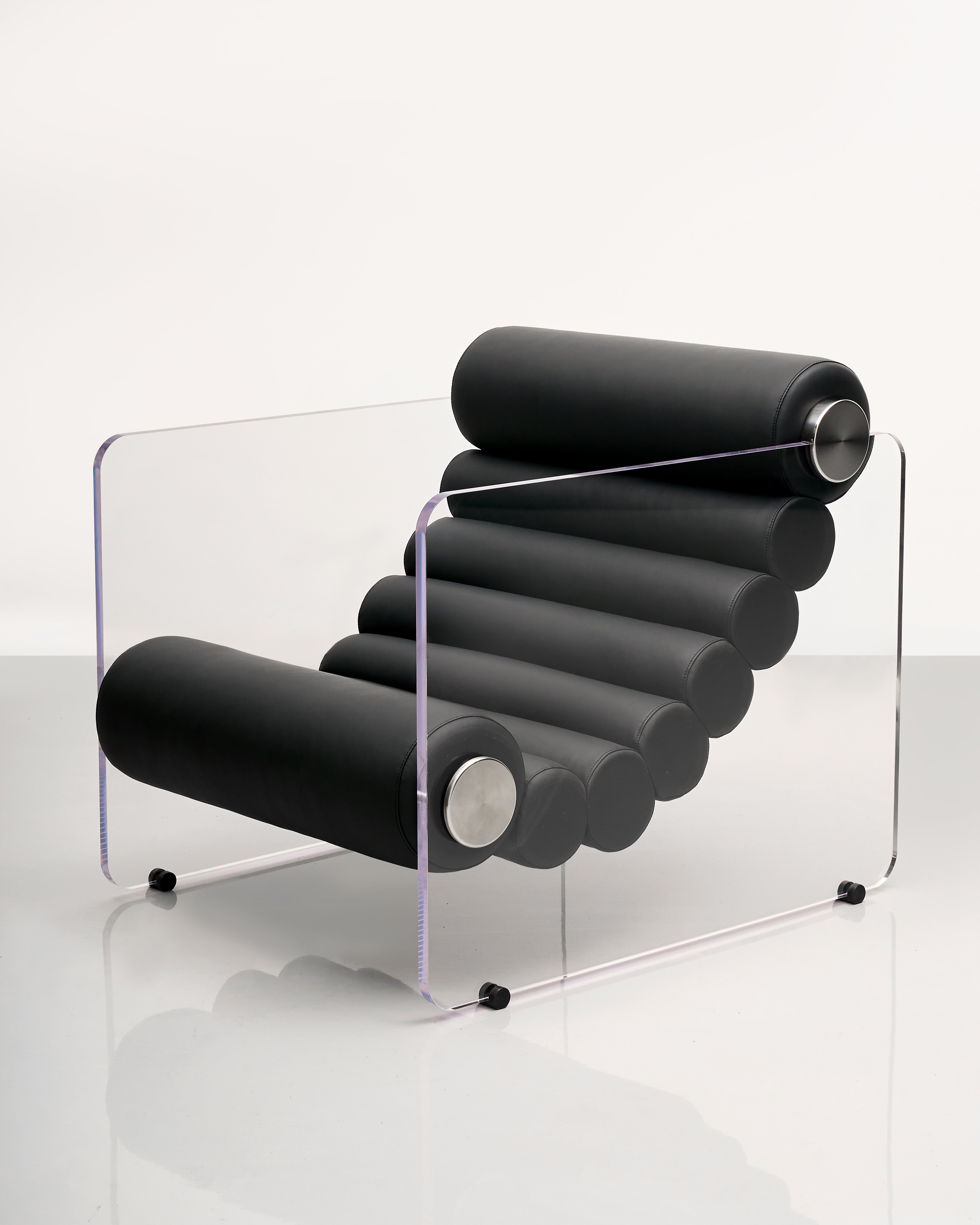 Modern black lounge chair with clear acrylic base on the sides on a white background