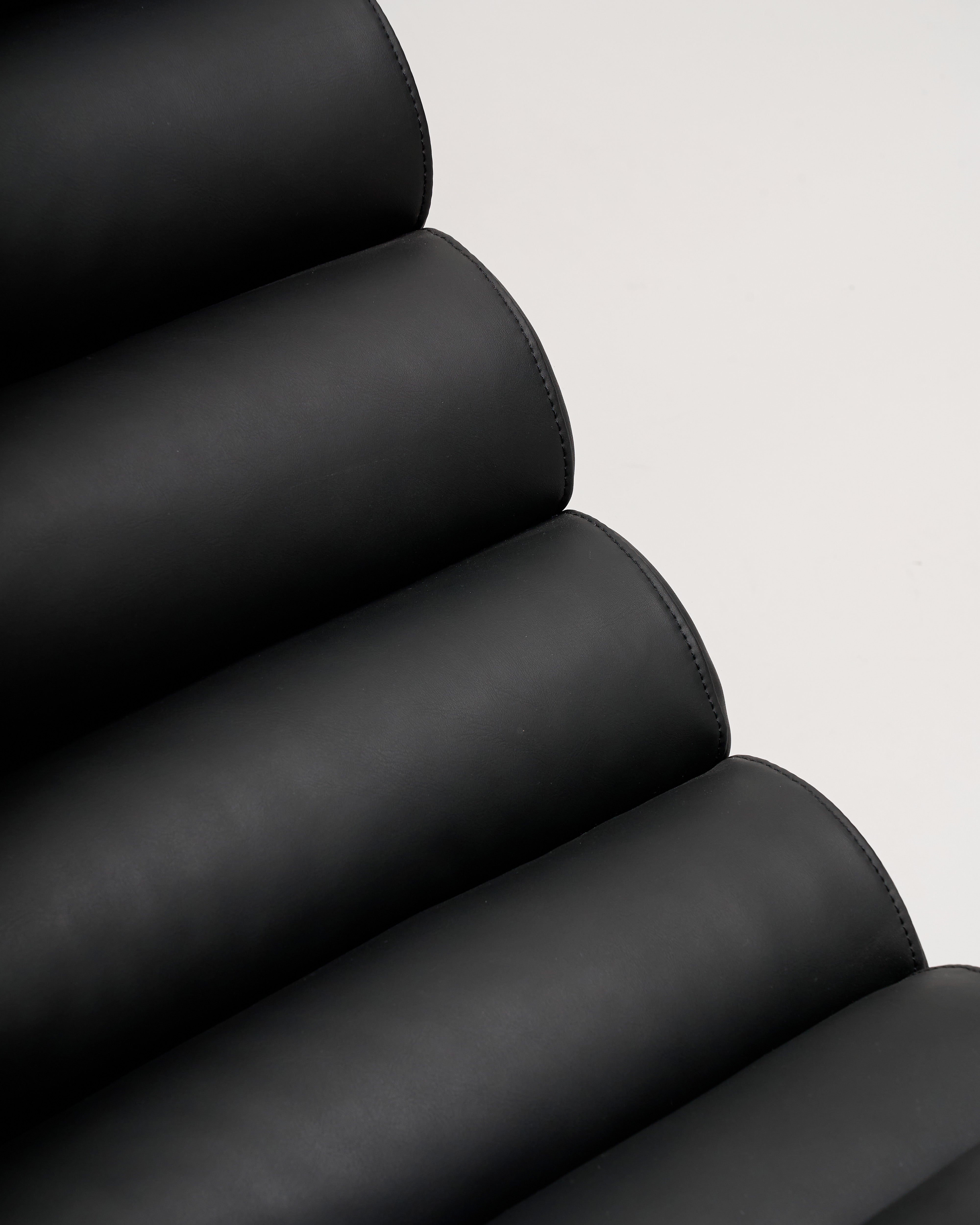Close-up of a black leather chair with a light gray background