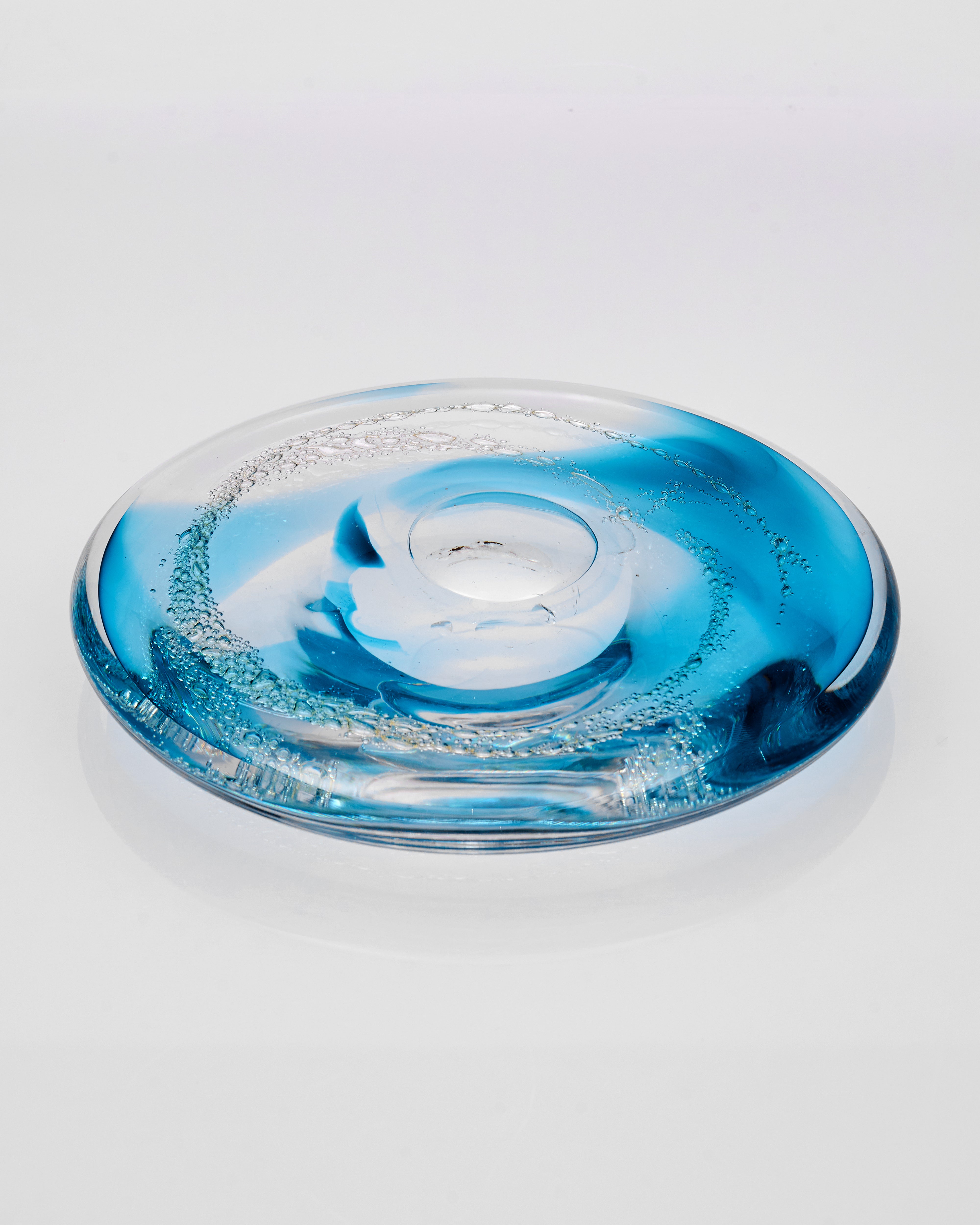 Clear glass object with blue and white design on a light gray background