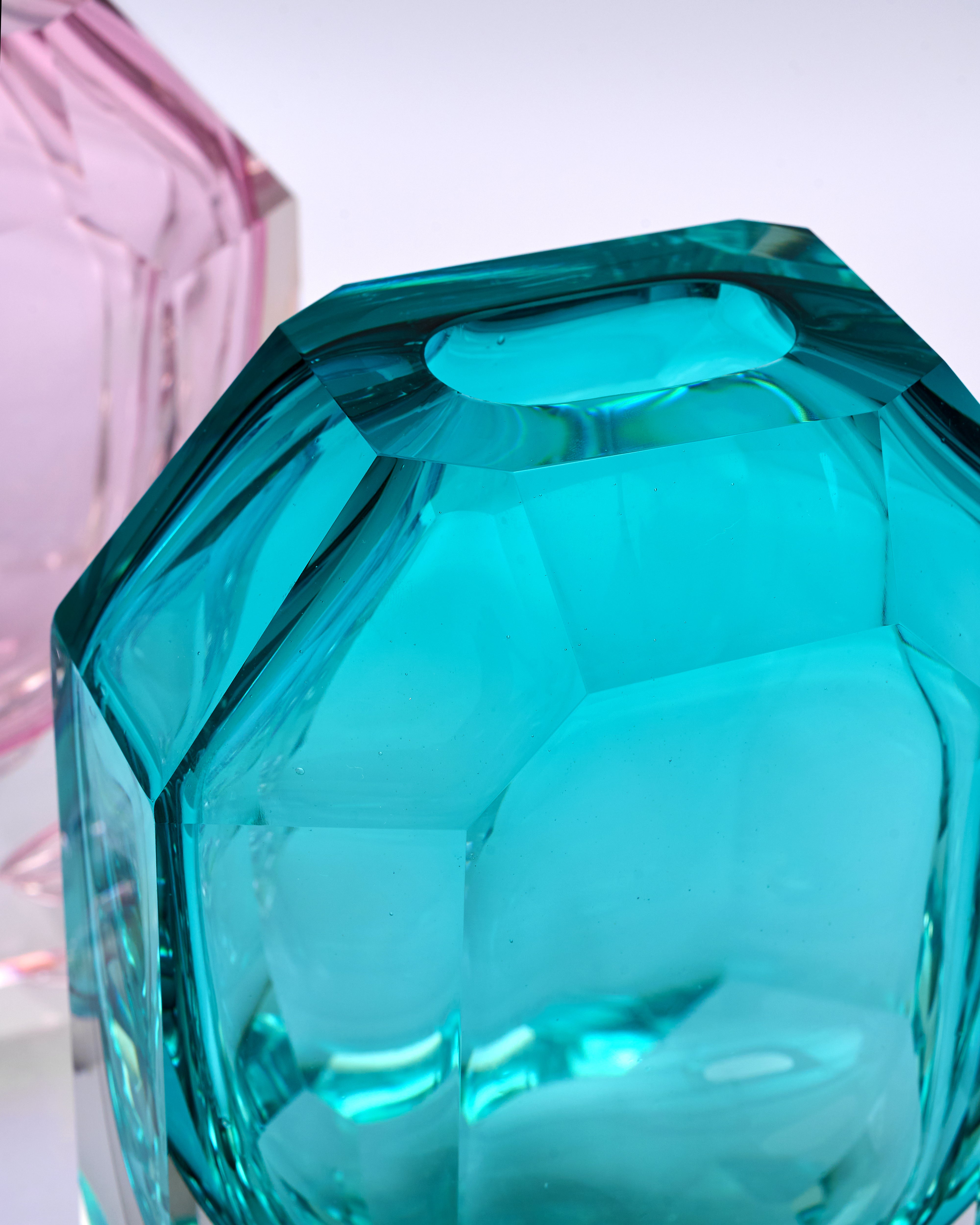 Teal glass vase with geometric design on a light background