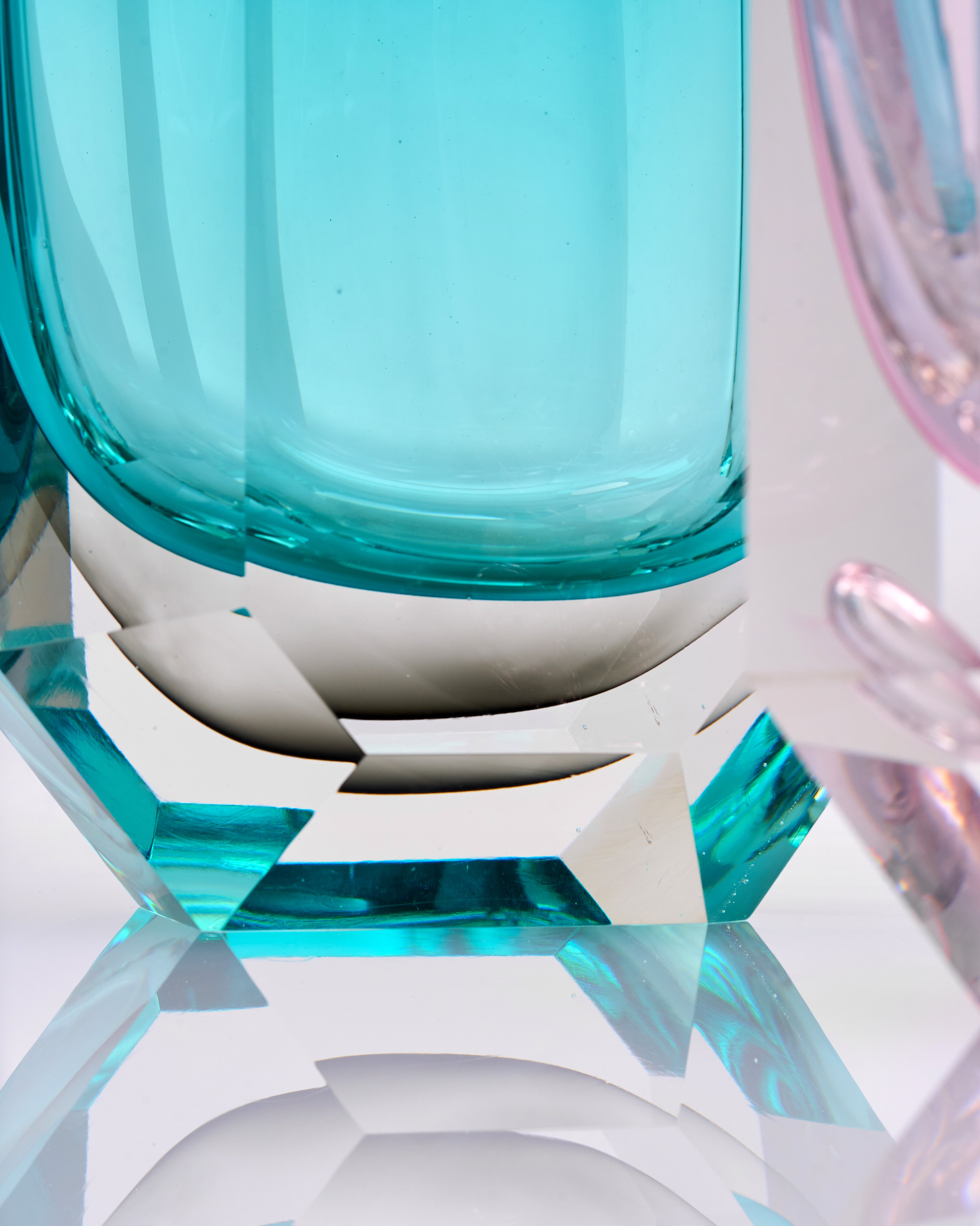 Close-up of a glass object with teal and white colors on a reflective surface.