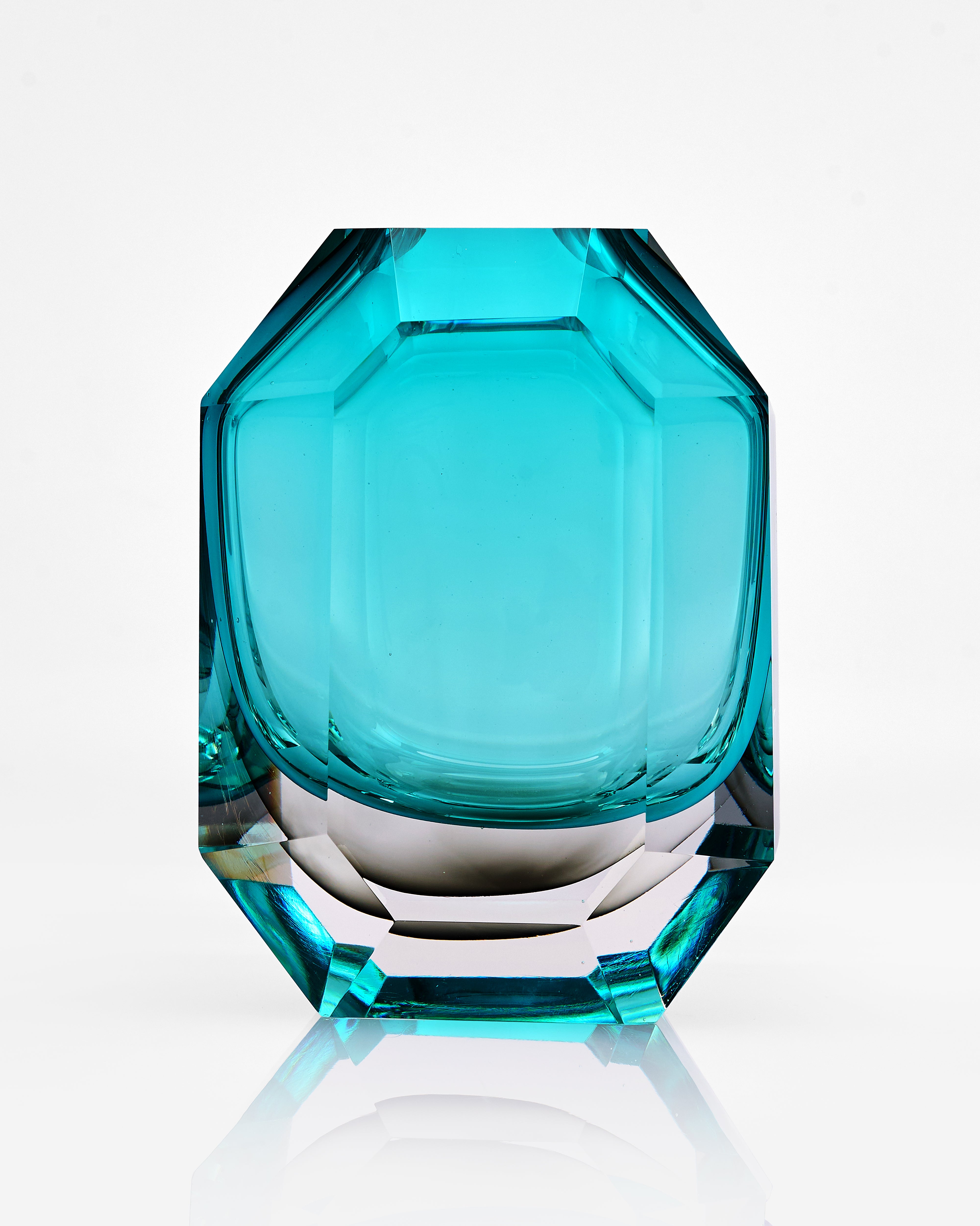 Turquoise glass vase with faceted design on a white background