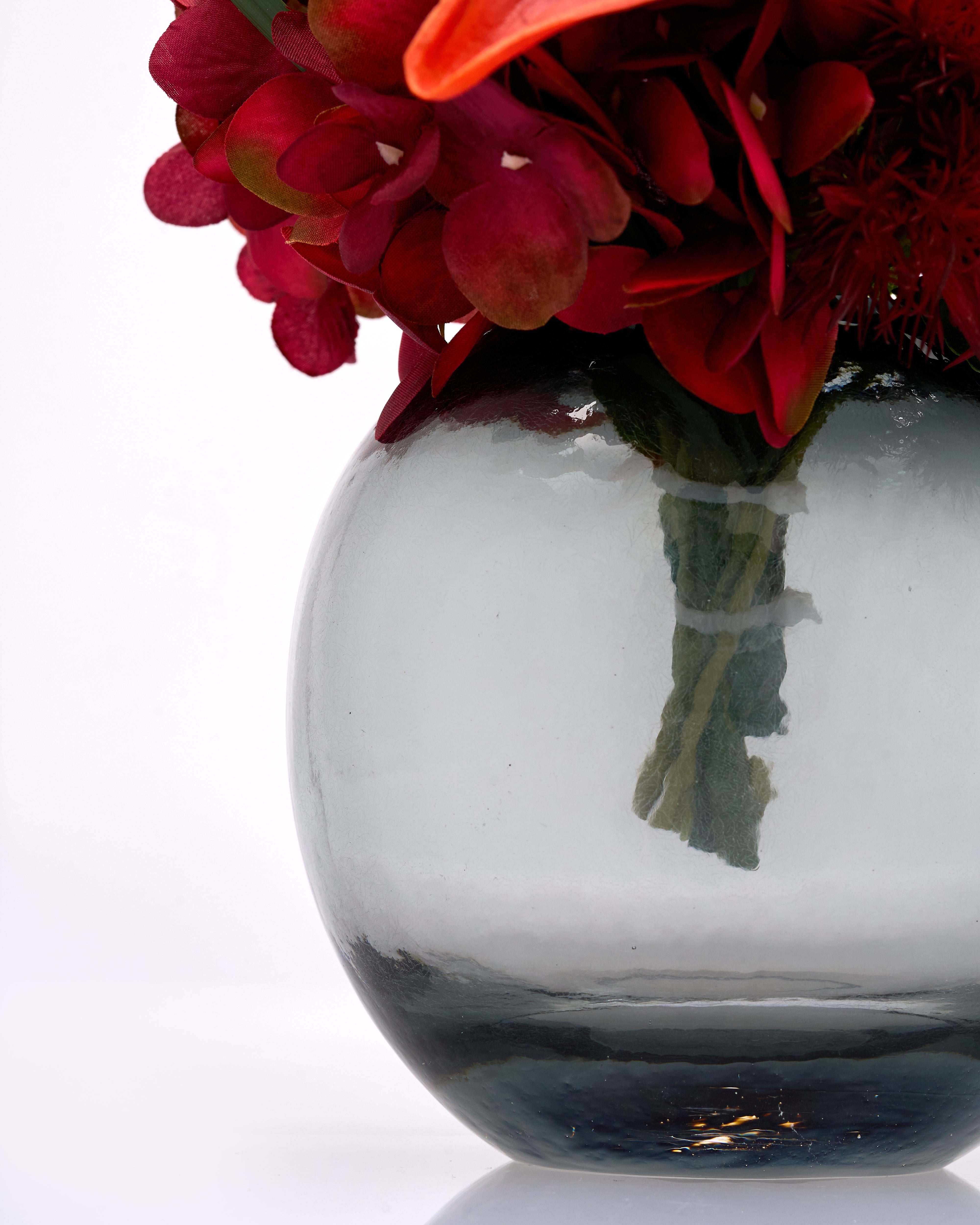 Clear glass vase with red flowers on a white background