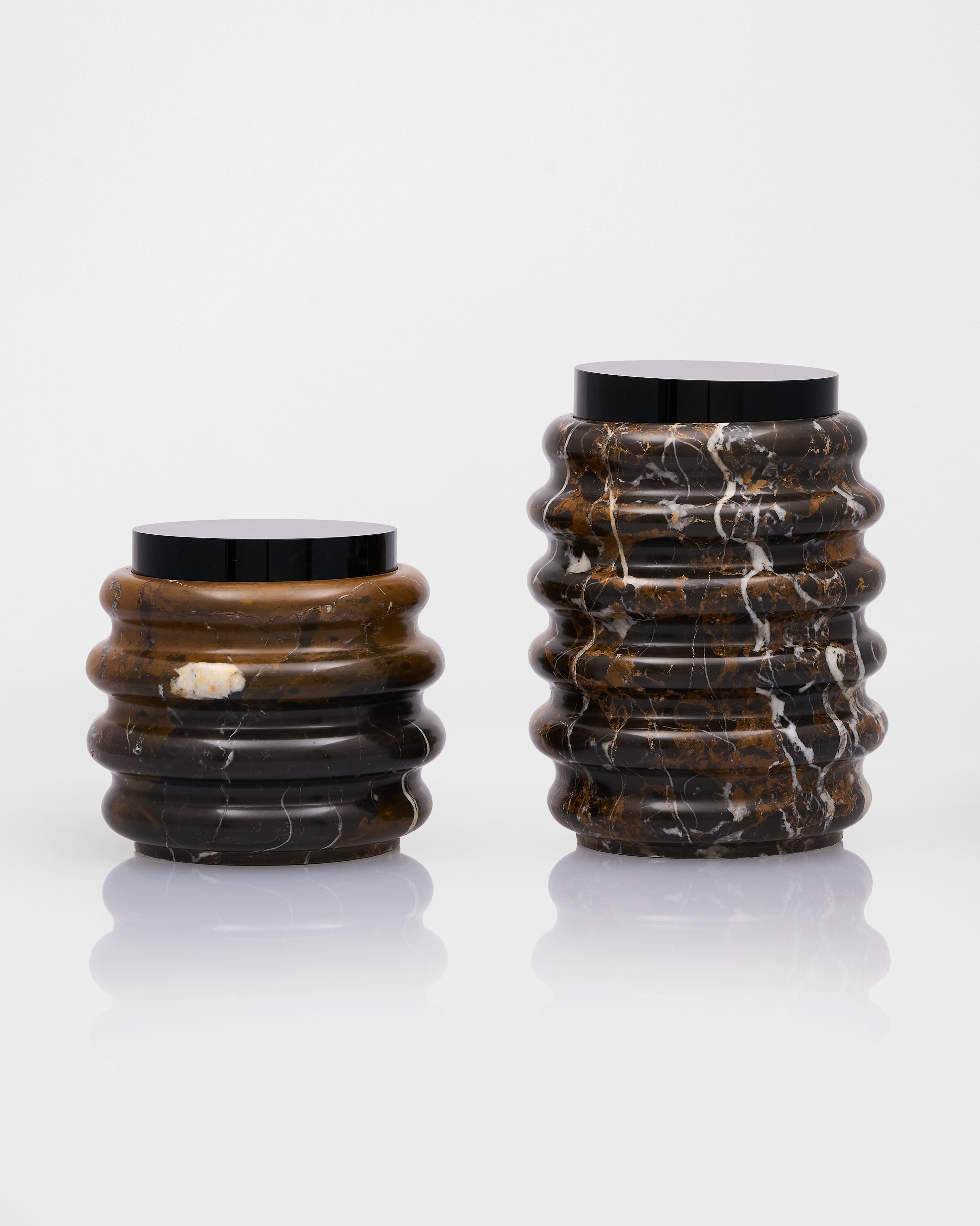 Two marble cylindrical vases with ribbed texture on a white background