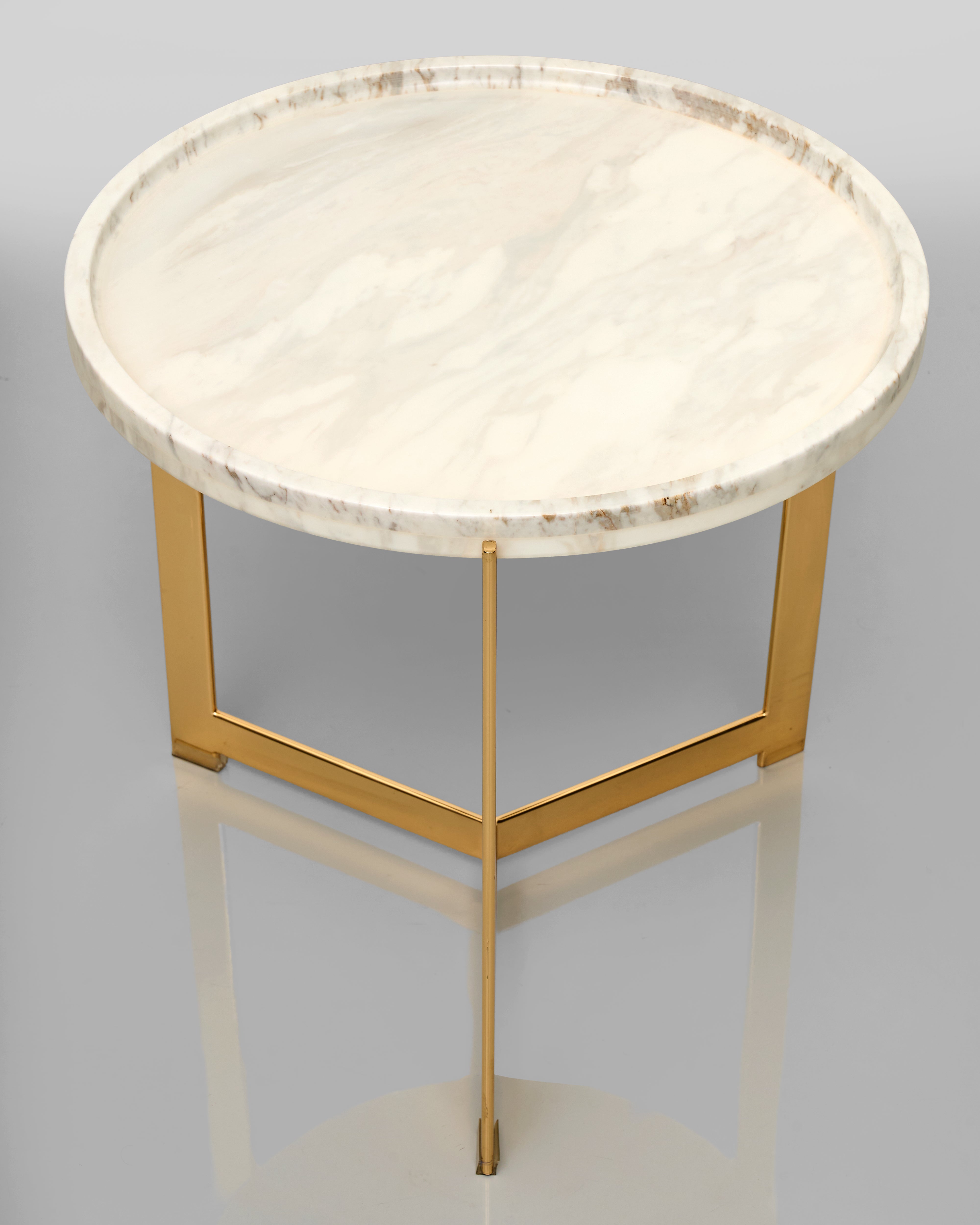 Round side table with marble top and gold metal frame on a gray background