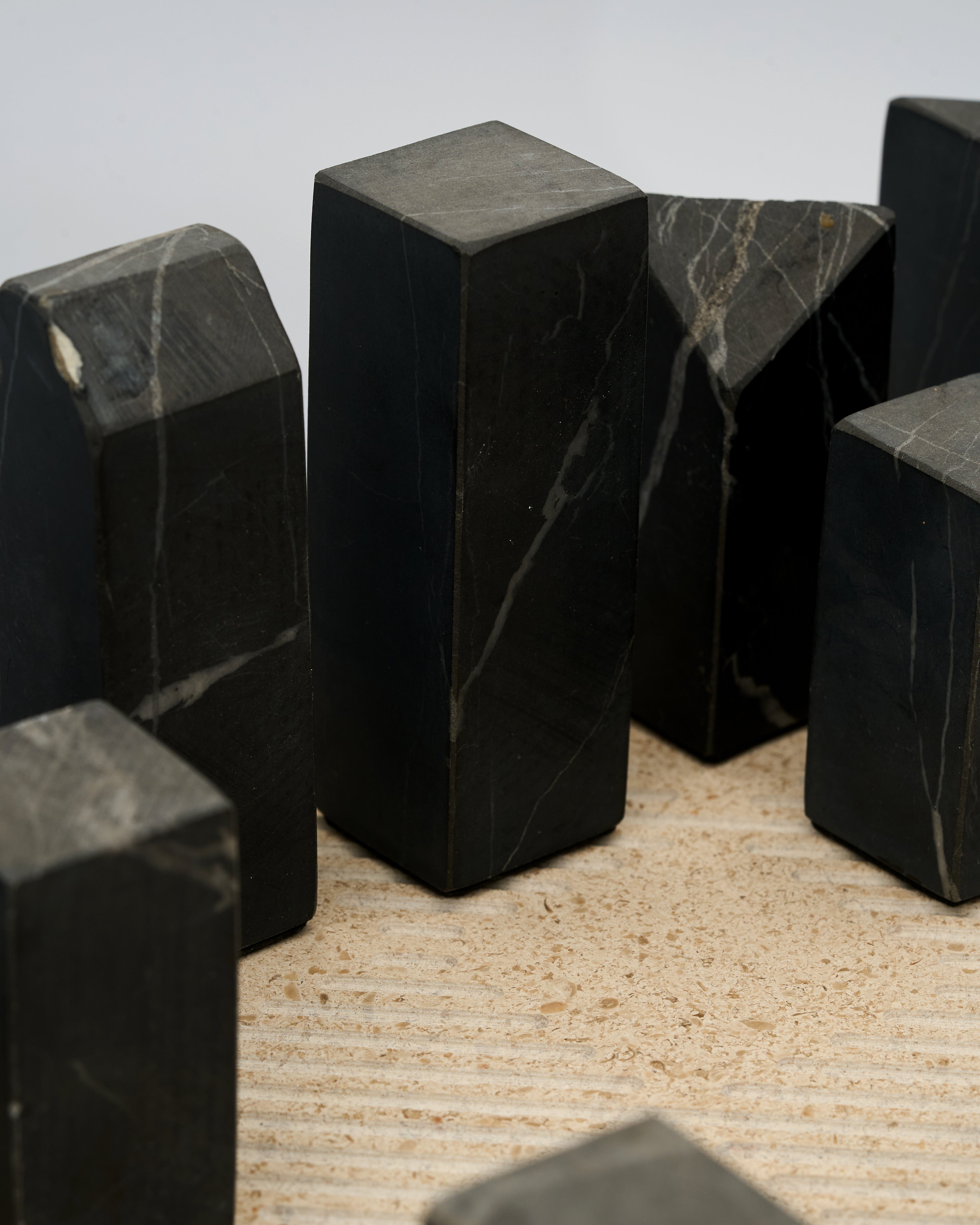 Black marble blocks of marble chessboard on a textured surface with a neutral background