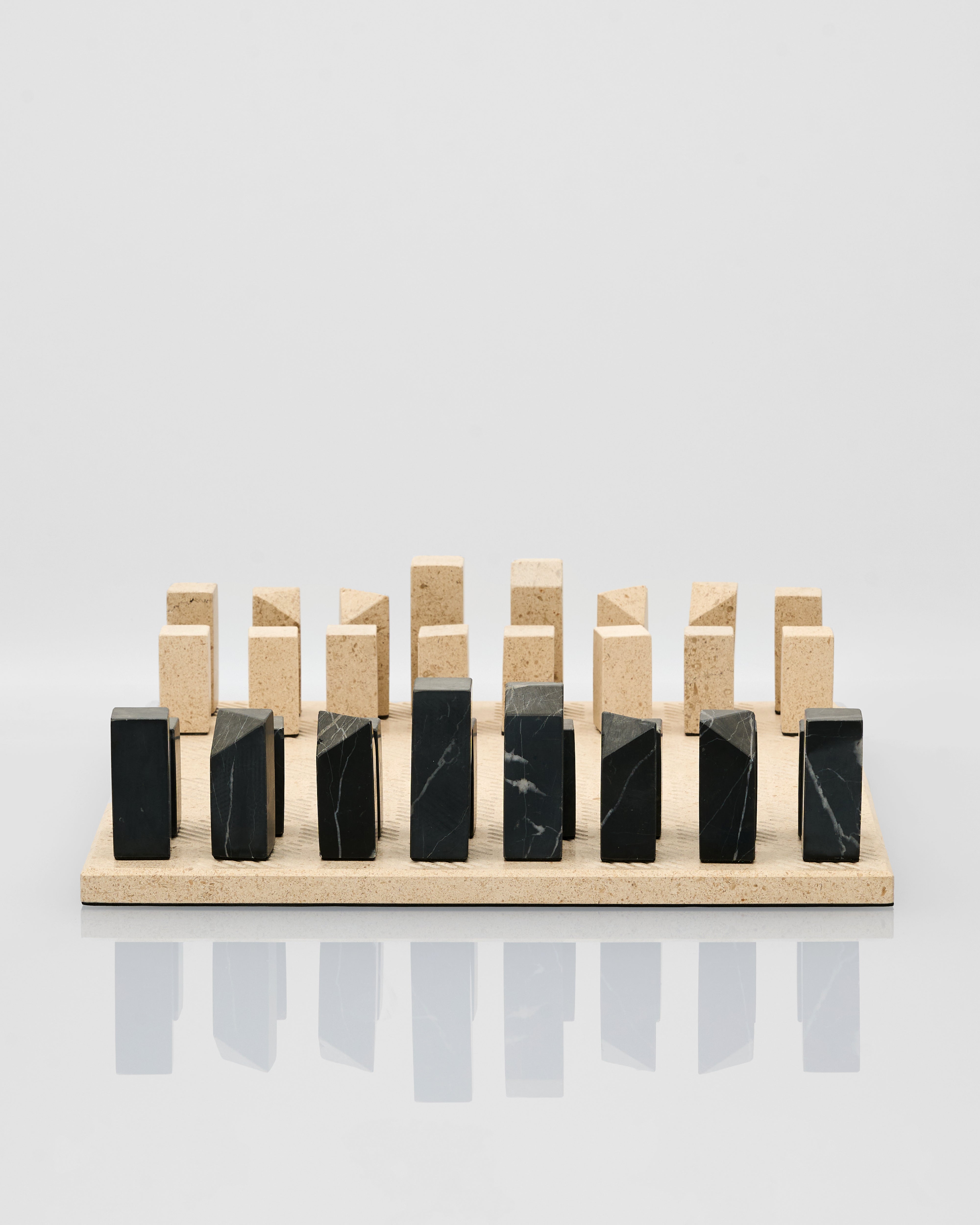 Set of black and beige geometric blocks of marble chess on a light gray background